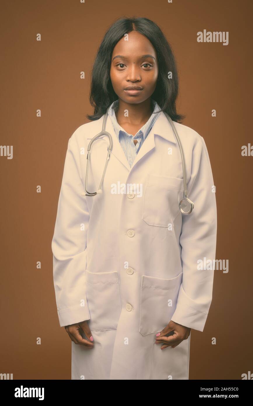 Studio shot of young beautiful African Zulu woman doctor against brown ...