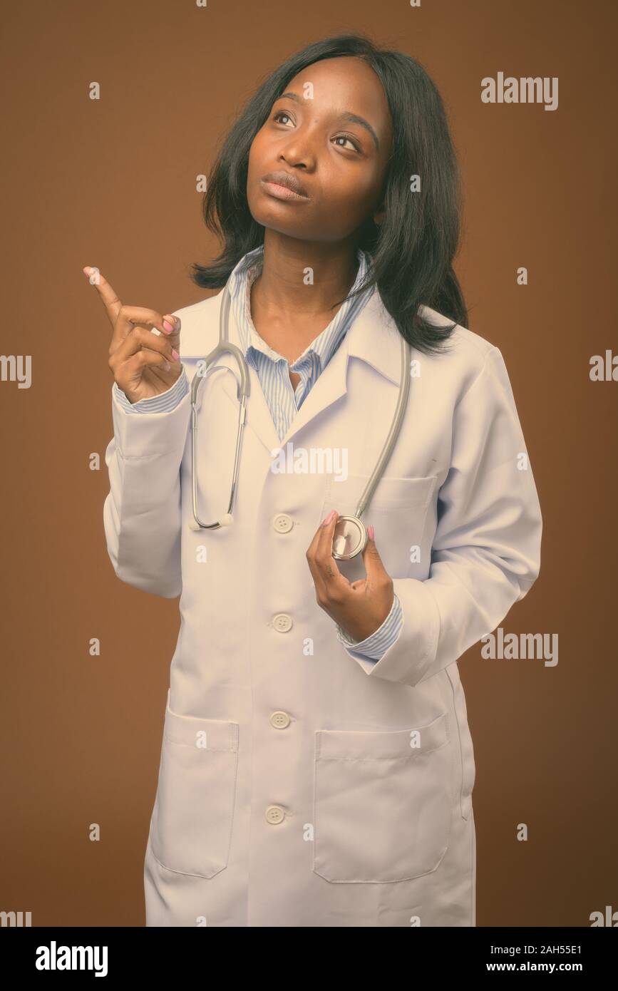 Studio shot of young beautiful African Zulu woman doctor against brown ...