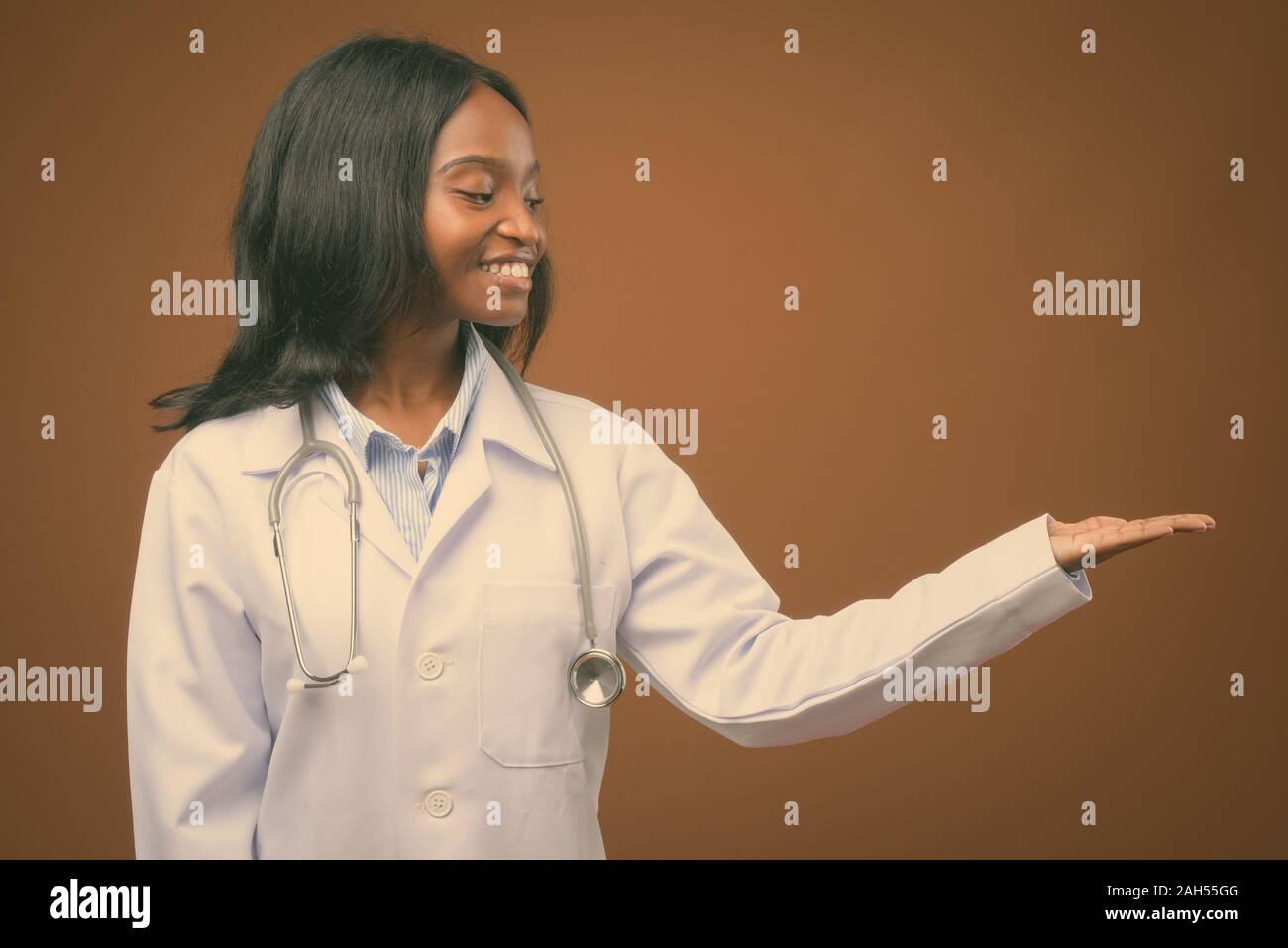 Studio shot of young beautiful African Zulu woman doctor against brown ...
