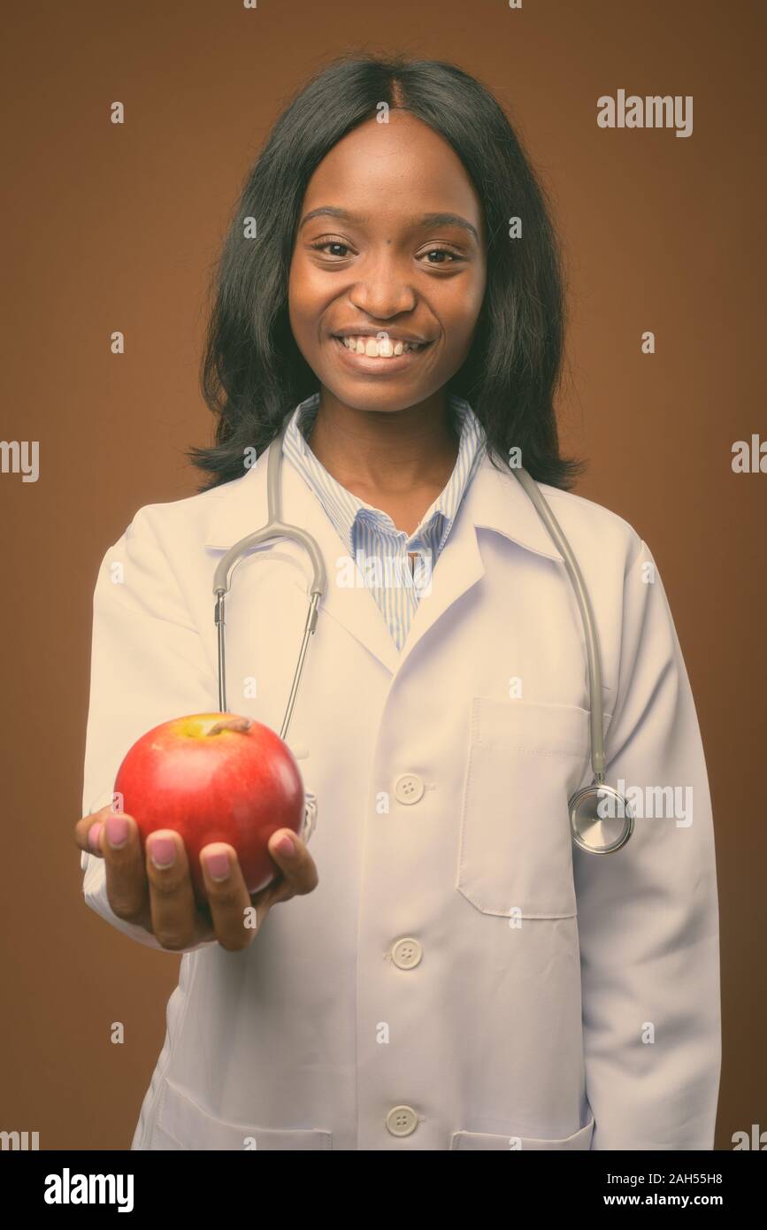 Studio shot of young beautiful African Zulu woman doctor against brown ...