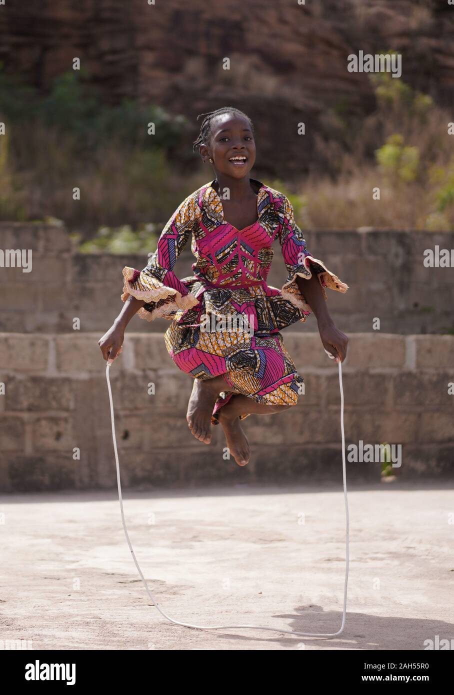 Smiling African Girl Jumping High With Her Skipping Rope With Both Legs At A Time Stock Photo