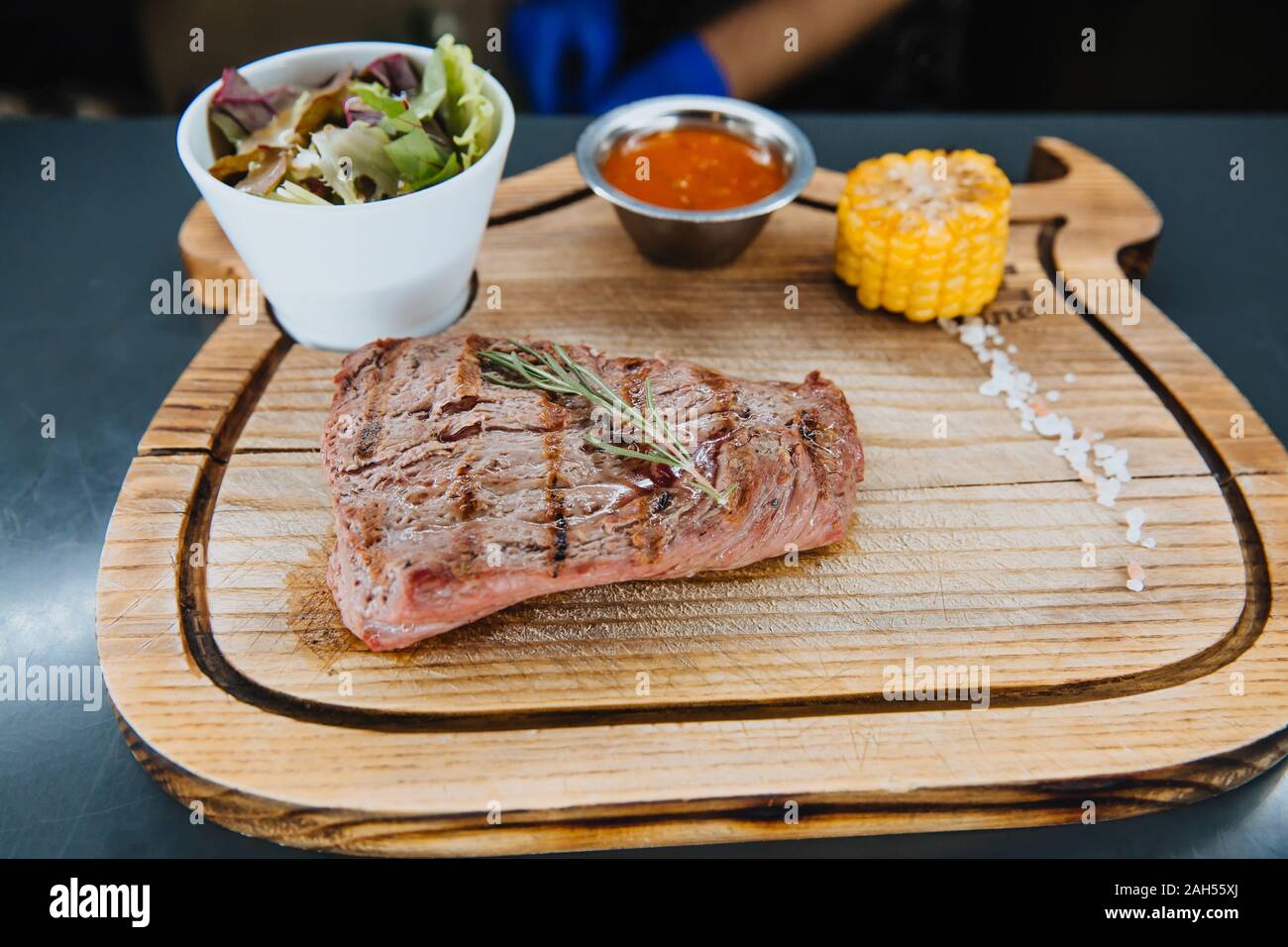 A juicy steak of grilled meat lies with a salad on a wooden Board. Stock Photo