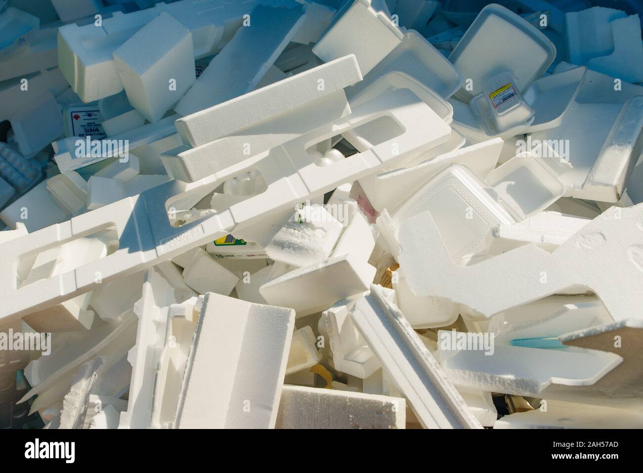 Close up white isolated photo of used foam thermocol plates with food stains heaped at a garbage