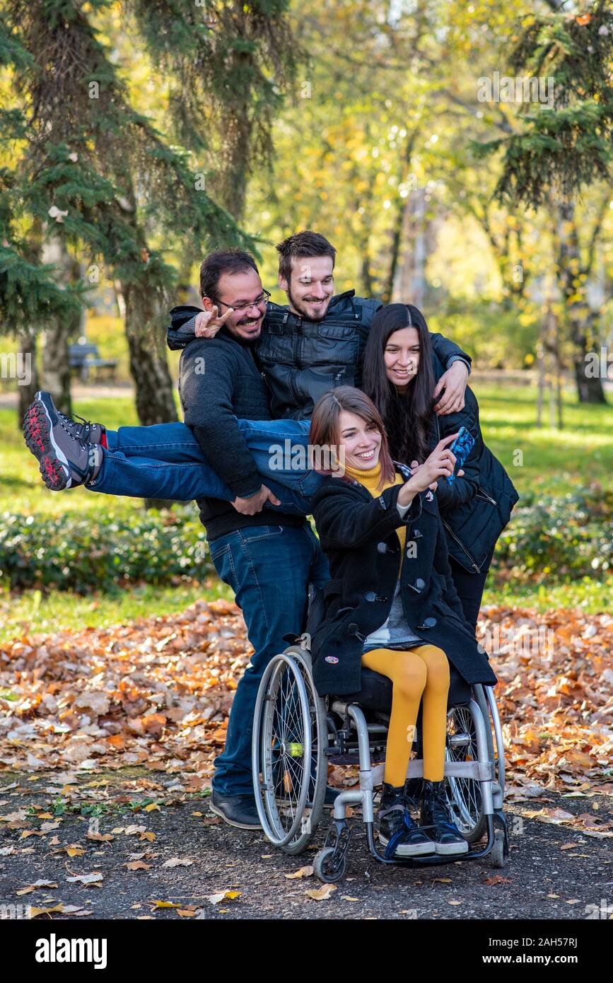 Young disabled woman in a wheelchair taking selfie with friends in a ...