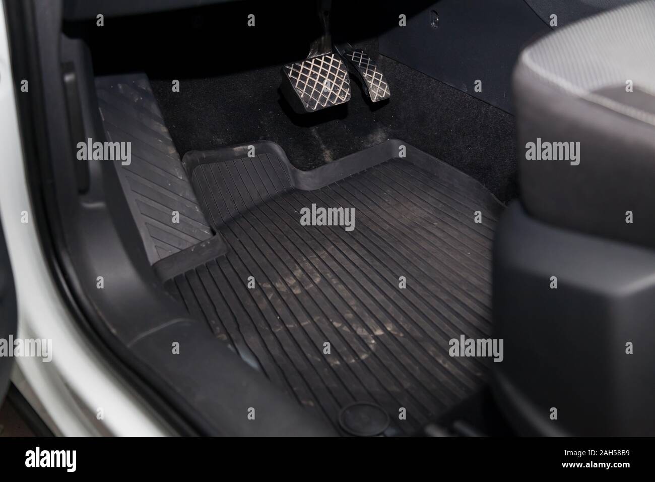 Dirty car floor mats of black rubber with gas pedals and brakes in the for the