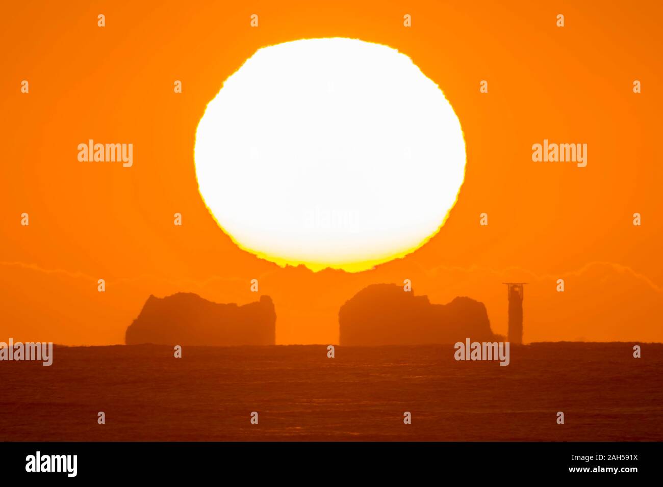 The Needles, Isle of Wight, UK.  25th December 2019. UK Weather.  The sun rises up from behind the Needles lighthouse on the Isle of Wight at dawn on Christmas Day.  Picture Credit: Graham Hunt/Alamy Live News Stock Photo