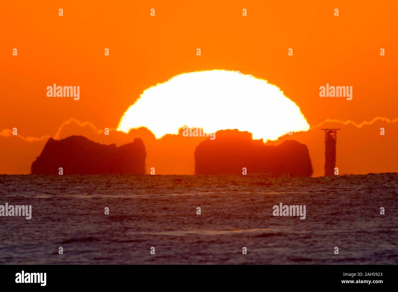 The Needles, Isle of Wight, UK.  25th December 2019. UK Weather.  The sun rises up from behind the Needles lighthouse on the Isle of Wight at dawn on Christmas Day.  Picture Credit: Graham Hunt/Alamy Live News Stock Photo