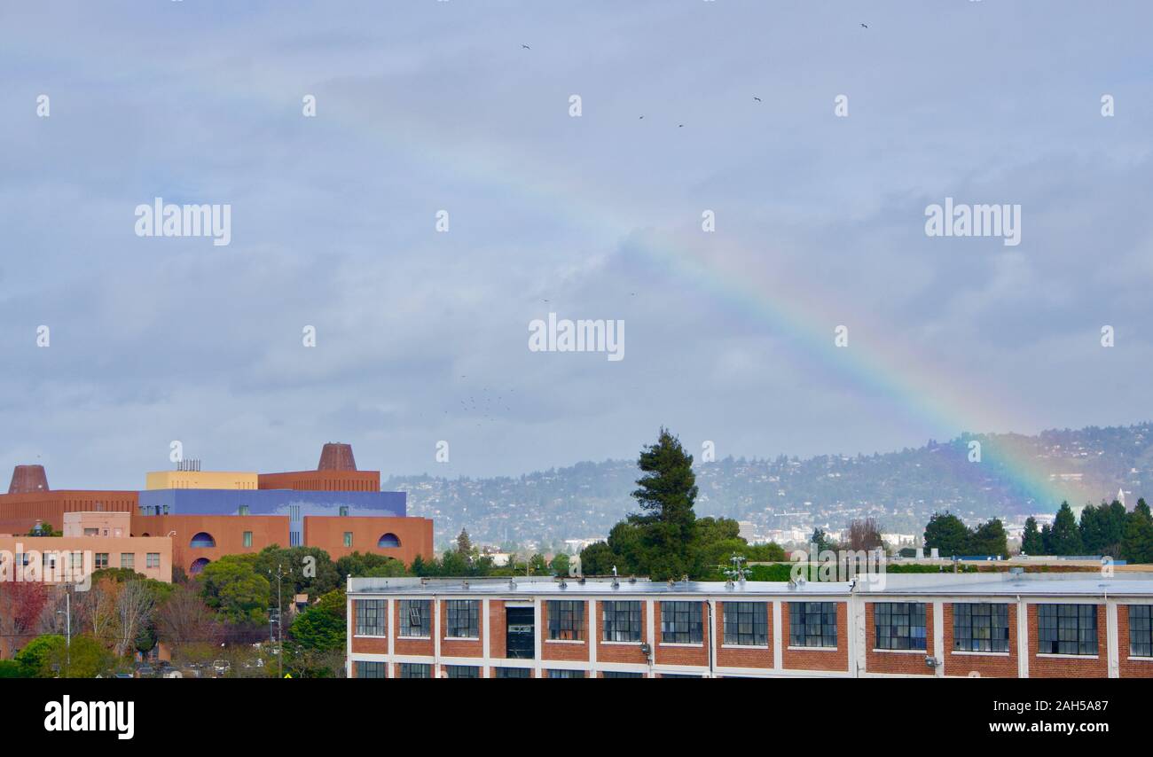 Rainbow over Emeryville above the Sherwin-Williams warehouse and former Novartis building or 'Emeryville Center of Innovation'. Berkeley Hills behind. Stock Photo