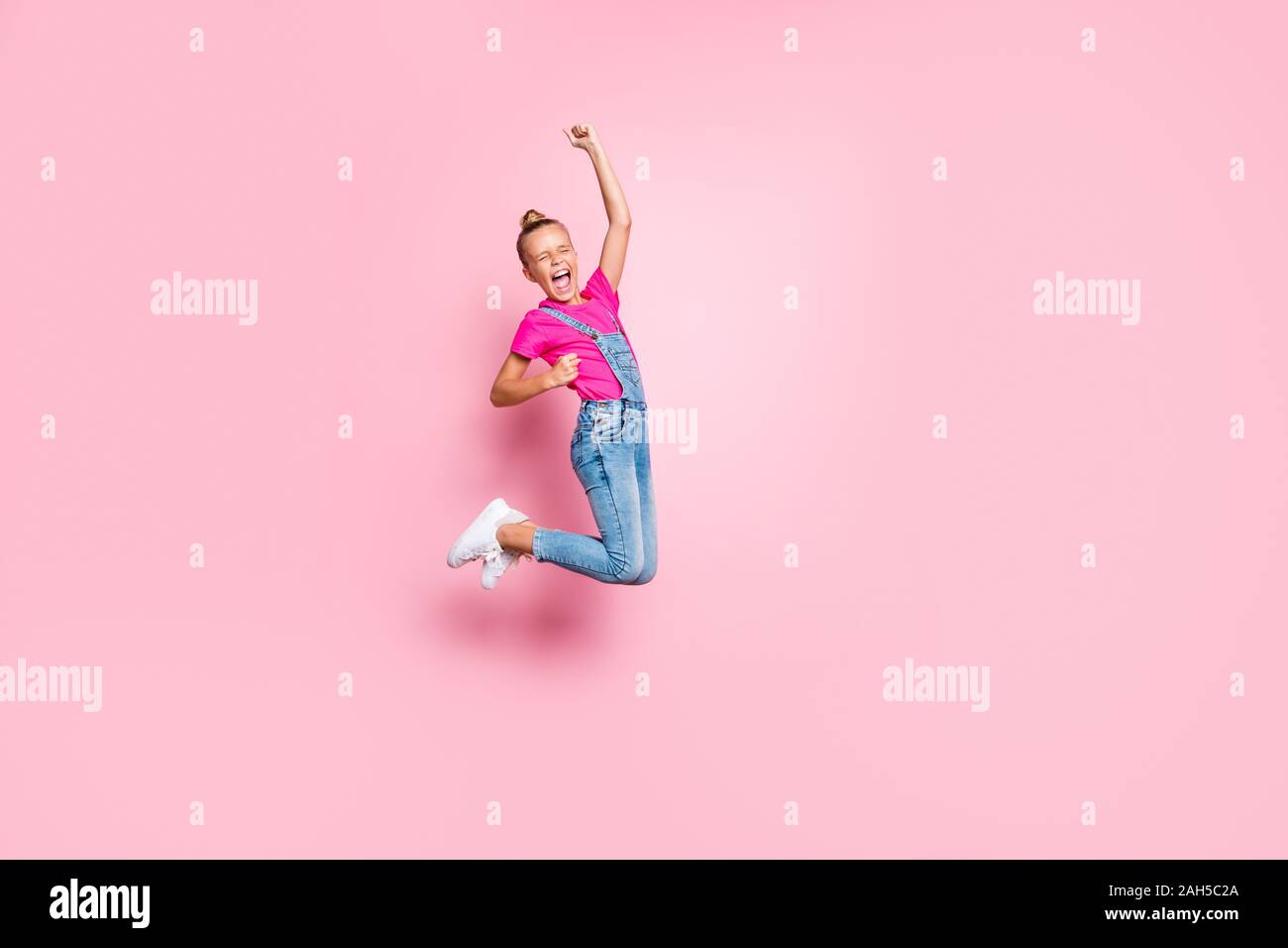 Full length body size photo of trendy cheerful ecstatic girl rejoicing with victory jumping crazily isolated over pastel pink color, background Stock Photo