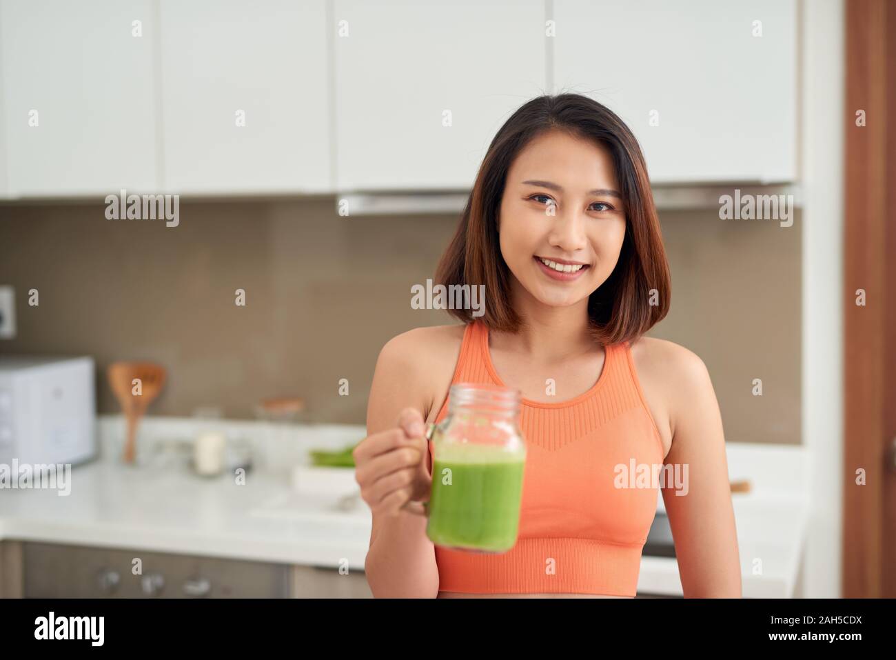 Pretty Asian woman drinking detox juice while wearing sportive clothing Stock Photo