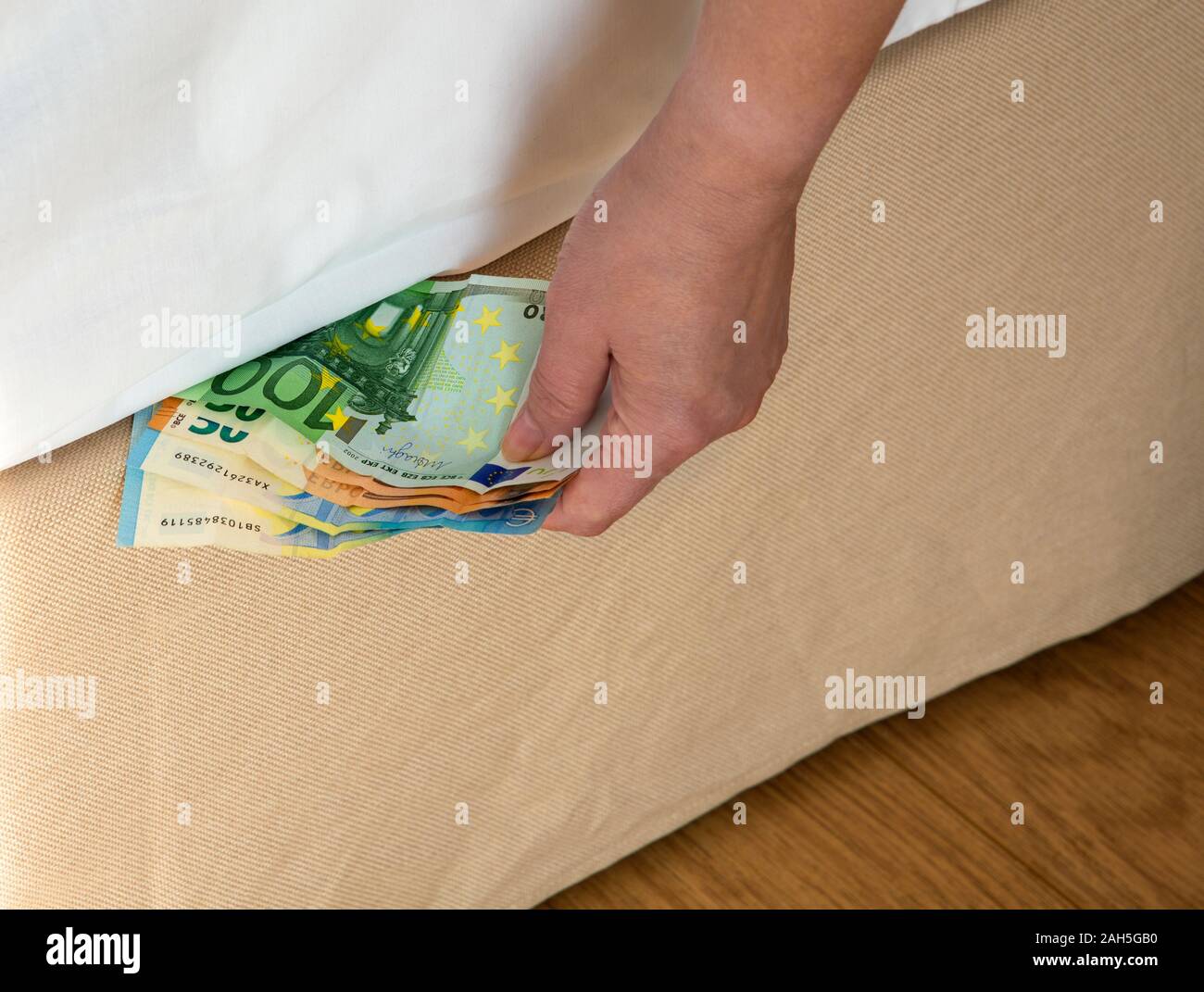 Putting money under the bed mattrac Stock Photo Alamy