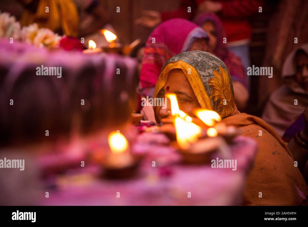 Woman lighting a candle while attending Holi celebrations inside Bankey