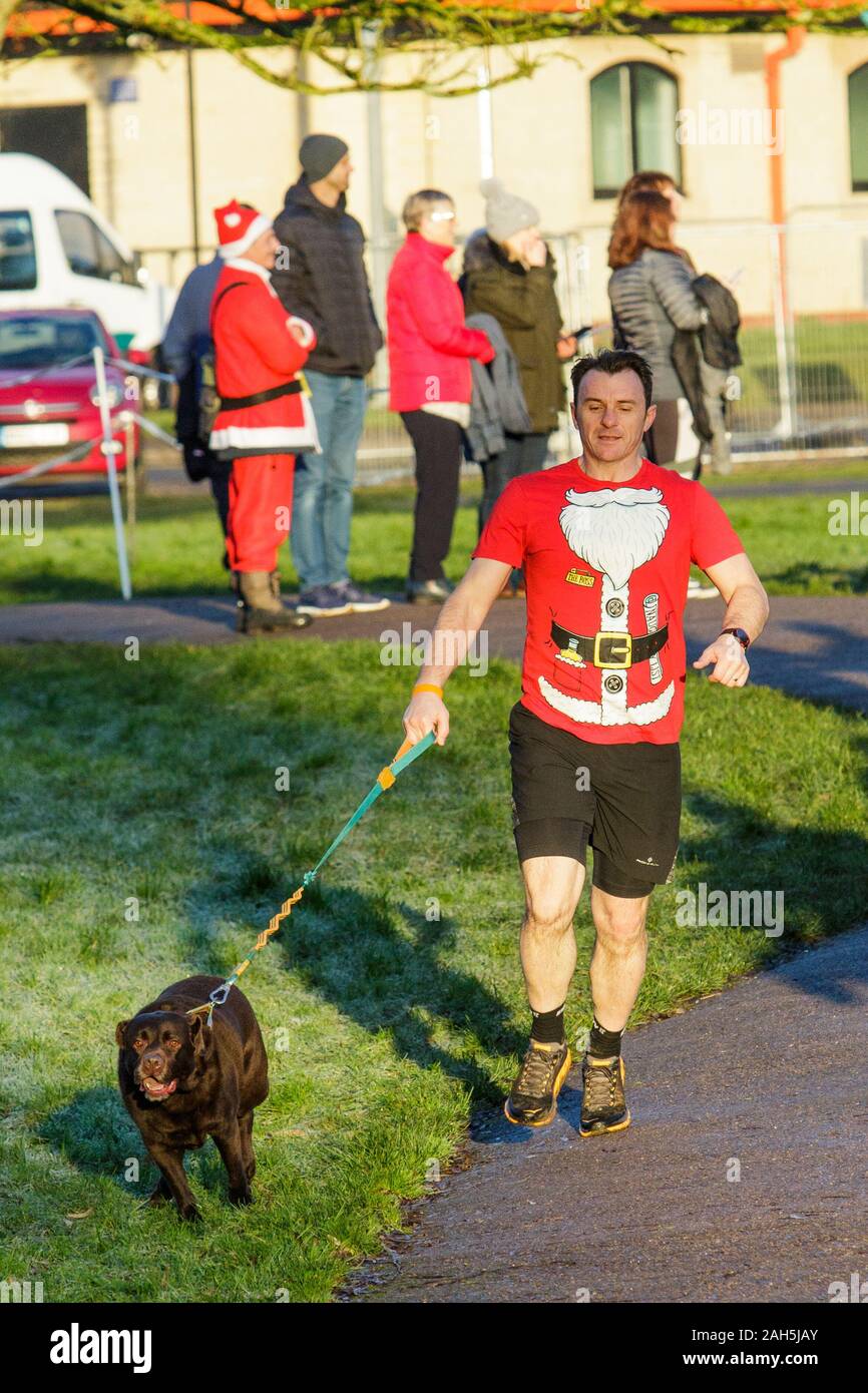 Chippenham, Wiltshire, UK. 25th December, 2019. A runner in fancy dress is pictured as he takes part in an early morning Christmas day 5km parkrun in Monkton Park, Chippenham, Wiltshire. 400-500 people participated in the event with many dressing up in fancy dress. Credit: Lynchpics/Alamy Live News Stock Photo