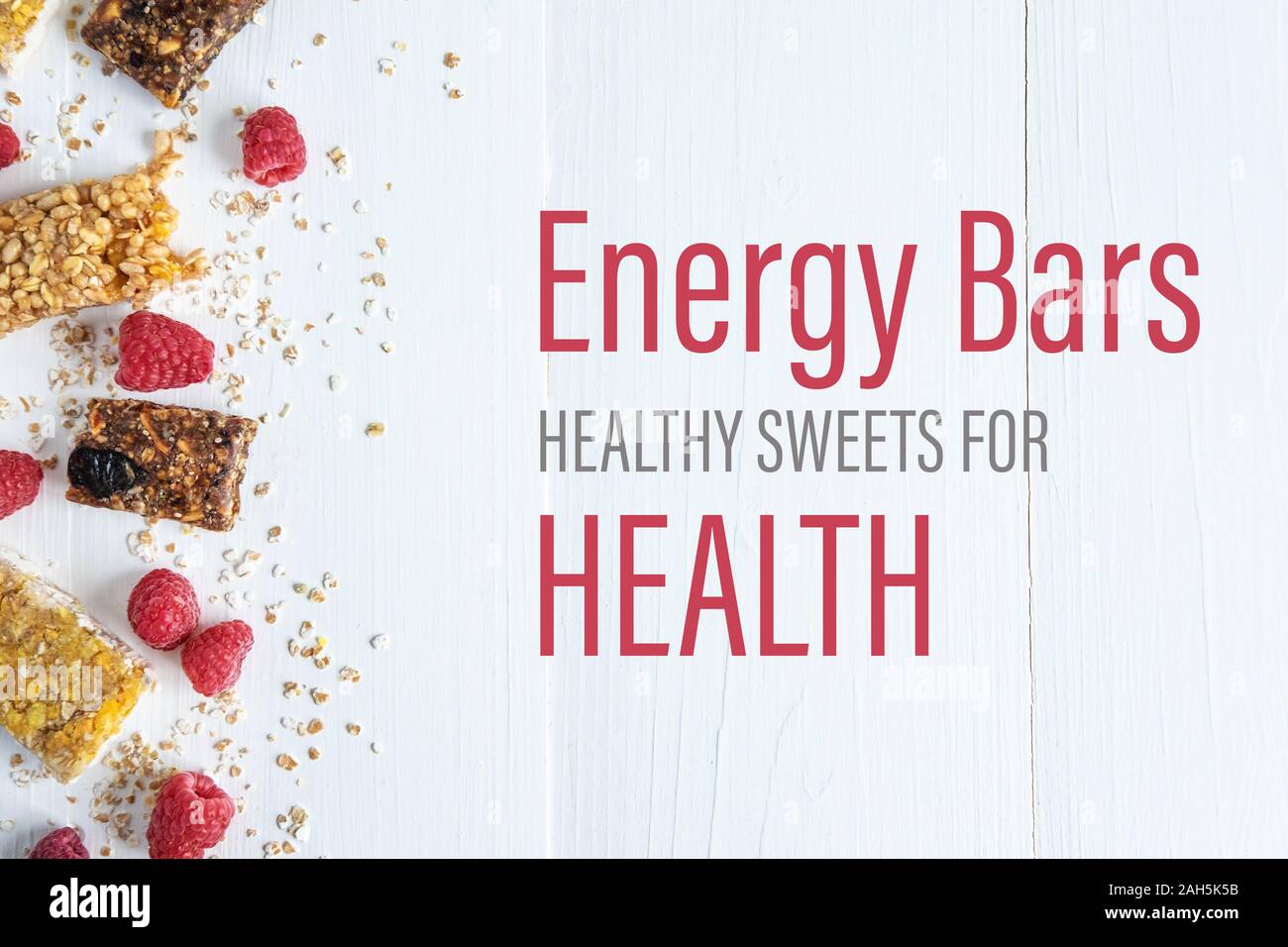 Energy bars healthy sweets for health. The inscription on a white wooden background with granola and fresh raspberries. Stock Photo