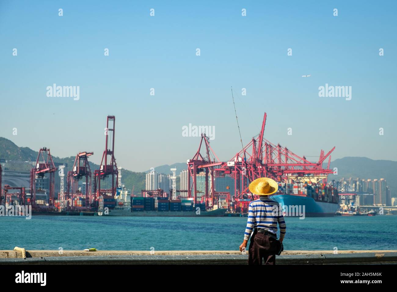 Fisher man with fishing rod from behind near container ship and freight
