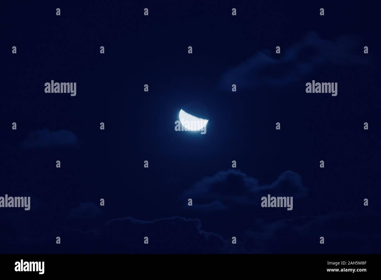 Half of bright moon among dark clouds in night sky with motion blur