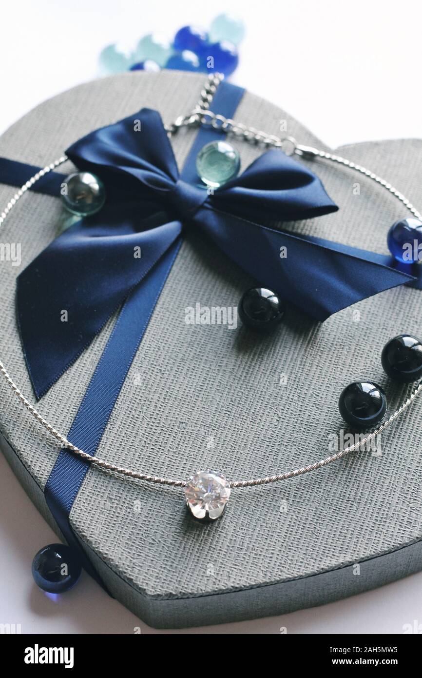 Princess choice. Jewelry composition on interior background and giftbox in blue color. Chainlet with tender gemstone for gift, New Year, Christmas, ma Stock Photo