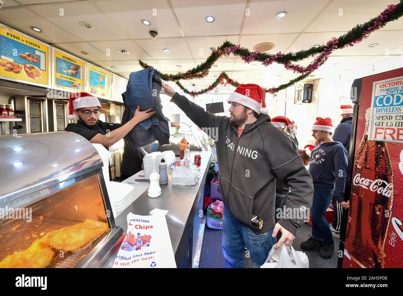 Daniel Jenkins, 34, is given fish and chips and extra clothing from donations as staff serve free portions of fish and chips to the homeless, needy, elderly and vulnerable on Christmas Day. Stock Photo