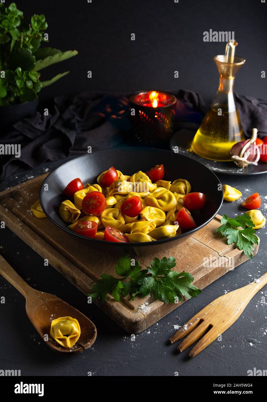 Ravioli with tomatoes on black plate in rustic homemade food environment, aerial view, dark food Stock Photo