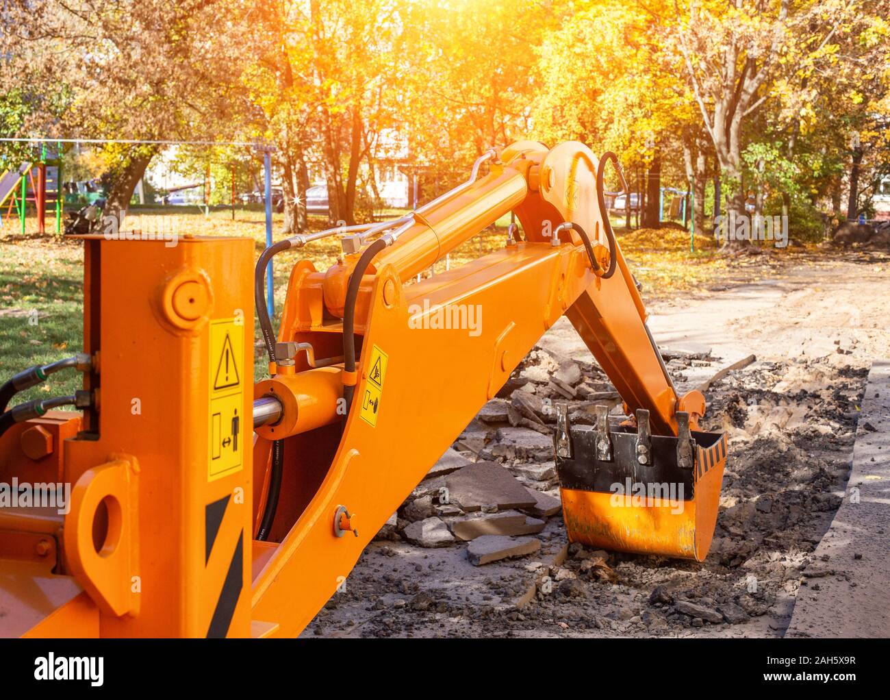 An excavator's rear bucket digs in the courtyard of a residential building. Replacement of heating main and pipes for water, industry Stock Photo