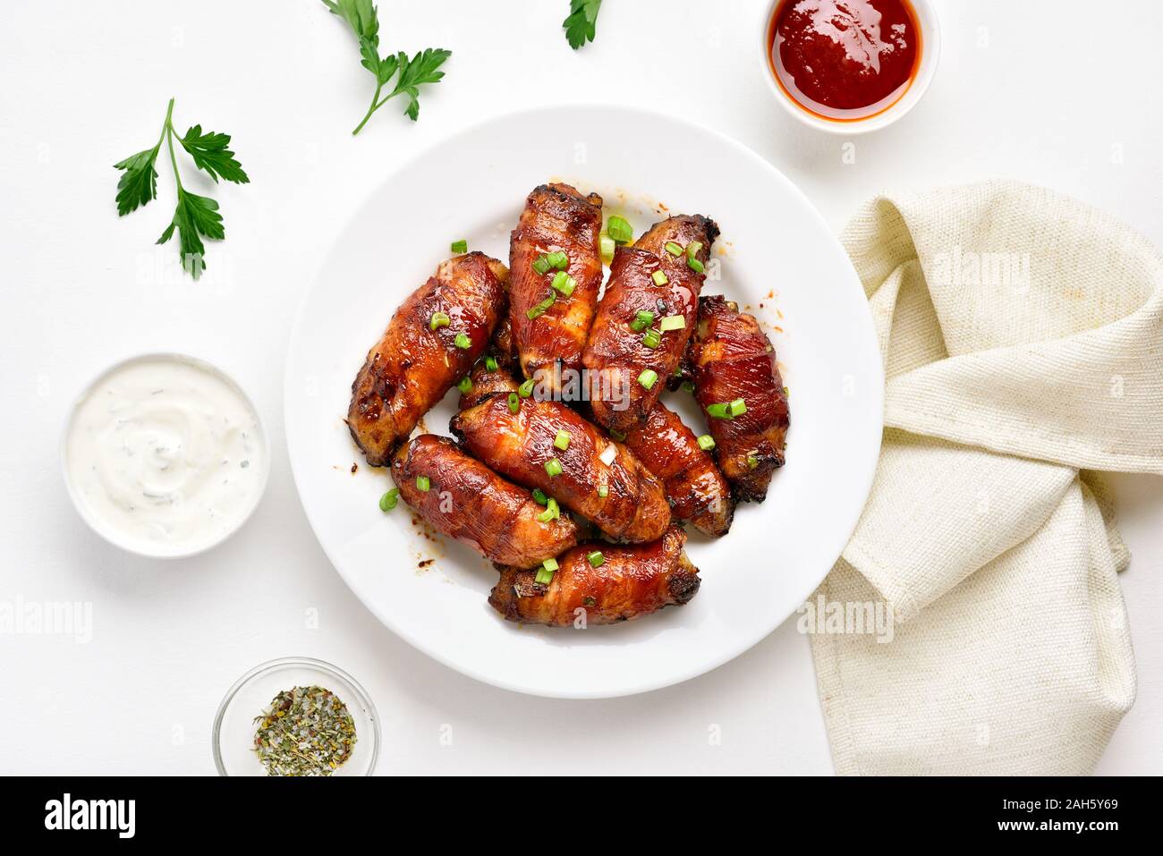 Bacon wrapped grilled chicken wings on plate over white stone