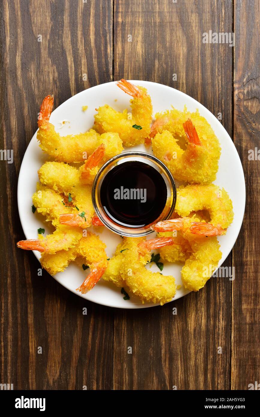 Deep fried breaded shrimp on plate on wooden background with free space
