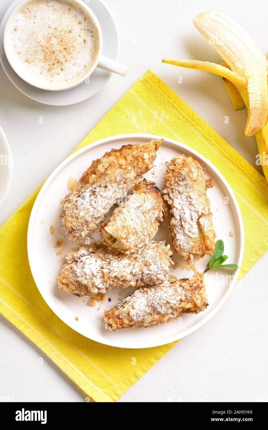 Deep fried bananas on plate over white stone background. Tasty dessert