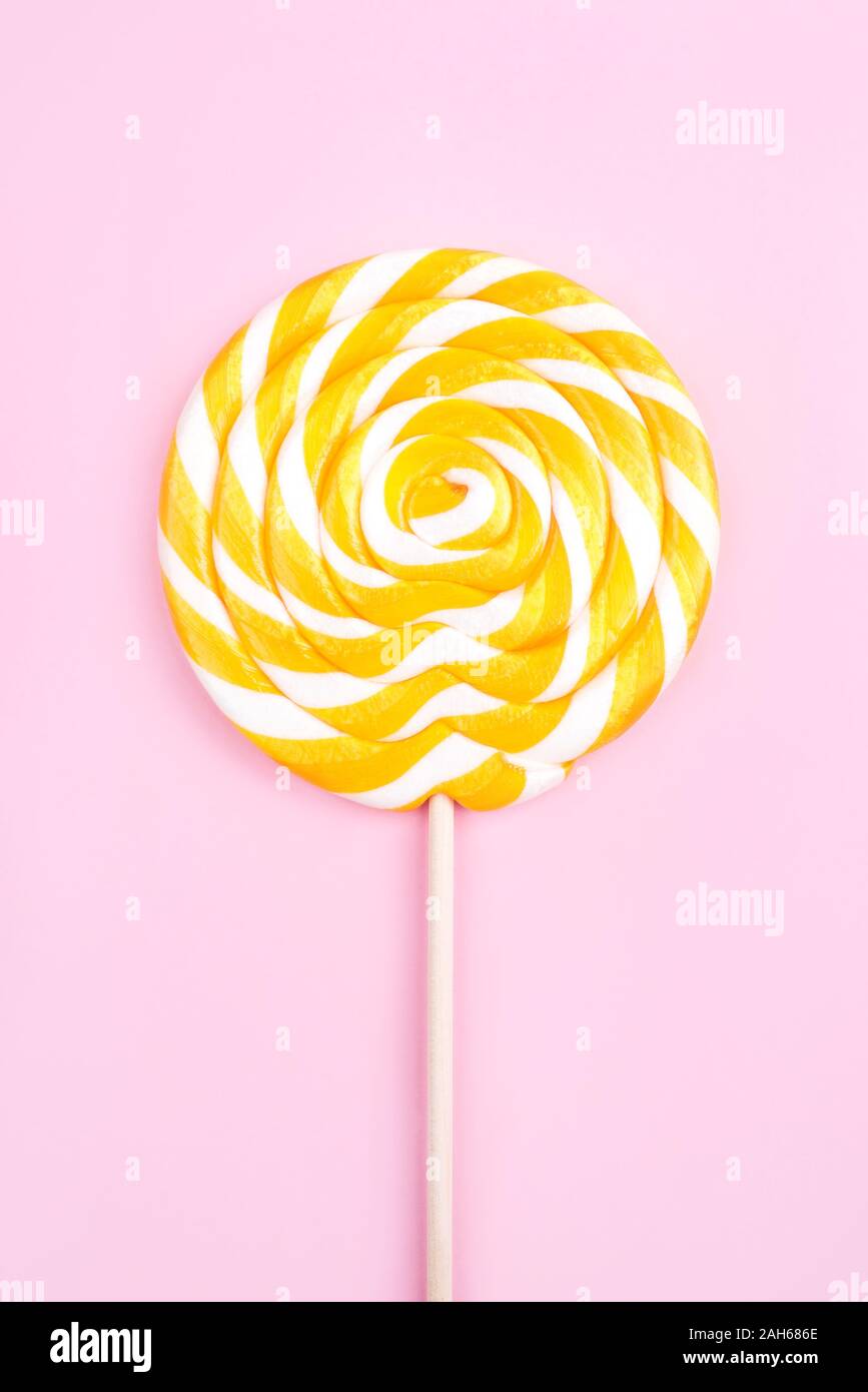 Yellow lollipop in the shape of a circle on a pink background Stock