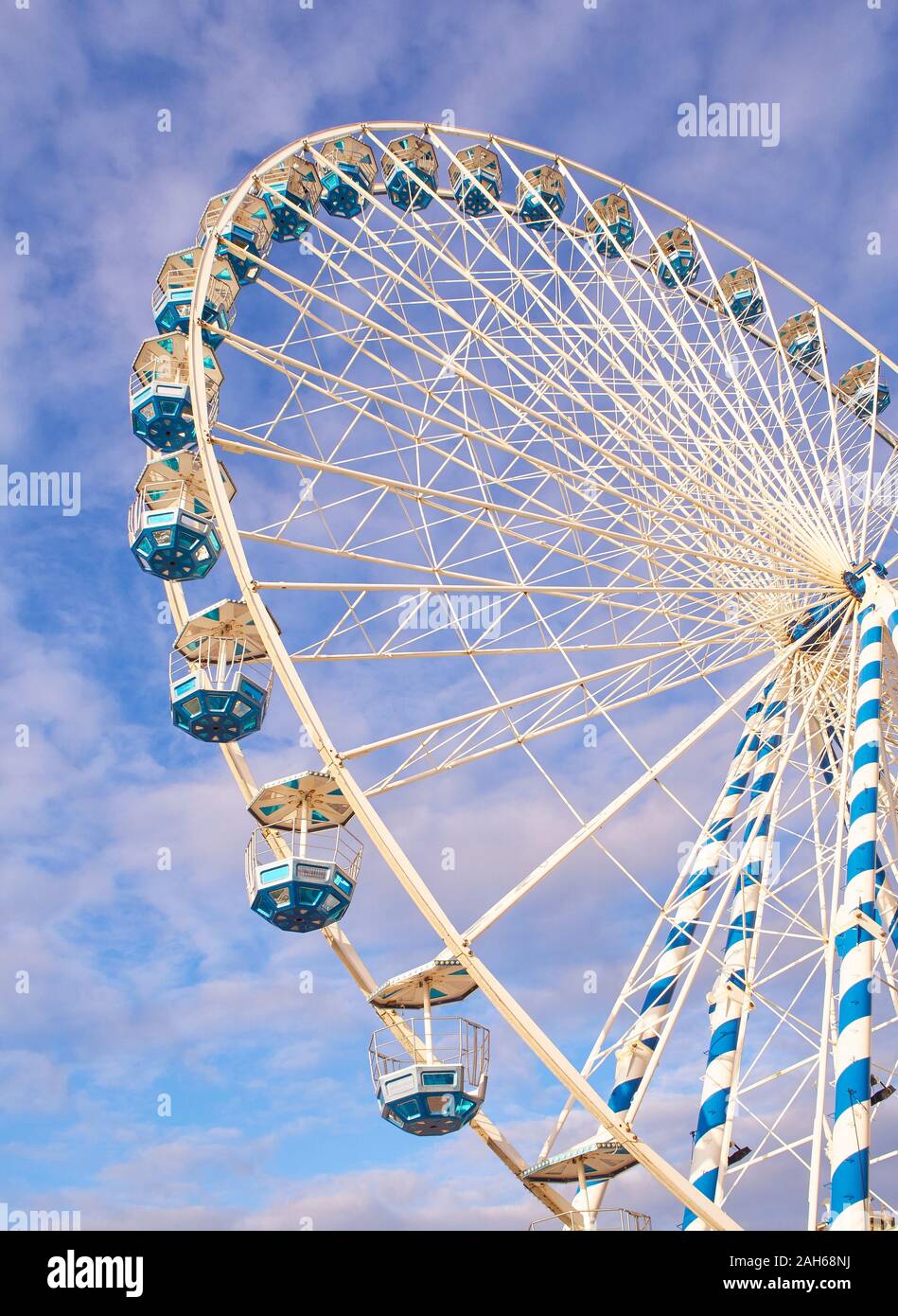 A metallic Ferris wheel with a cloudy sky in the background. Stock Photo