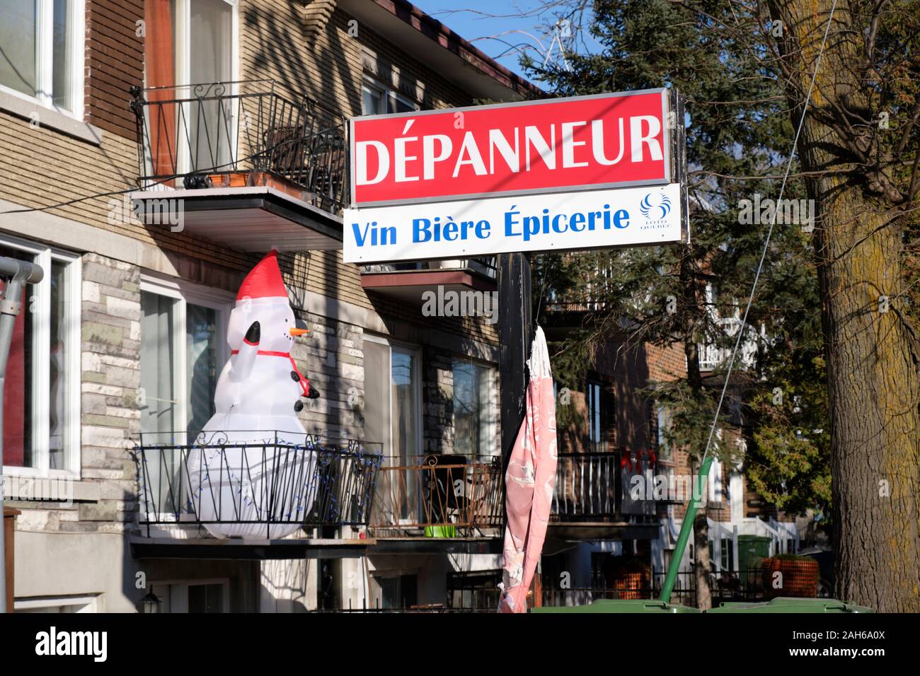 Montreal corner store sign 'Dépanneur- Vin Biere' on a sunny day with inflatable snow man on balcony Stock Photo
