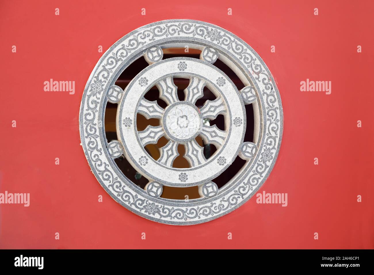 Stone rosette relief - window made of decorated stone relief, ornaments and relief on the red wall from Chinese buddhism temple, Fujian,China. Stock Photo