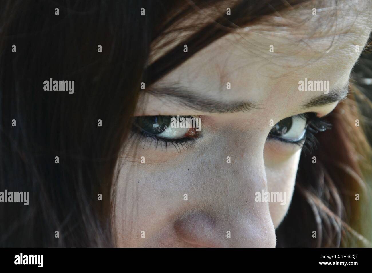 Close up of the eyes of a lady with brunette hair, eye liner and mascara, looking concerned and worried Stock Photo