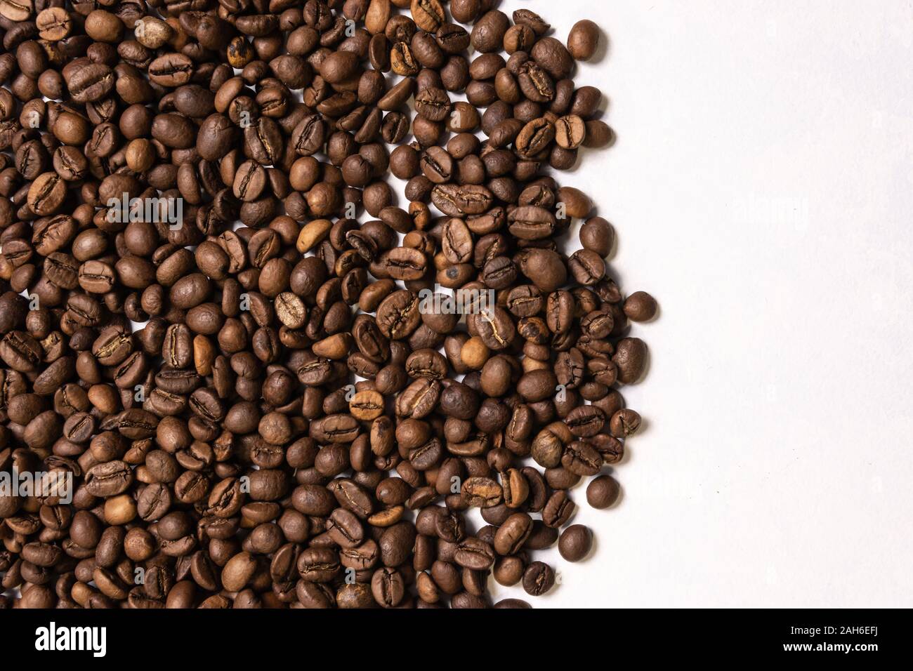 Roasted coffee beans in bulk on a light blue background. dark cofee ...