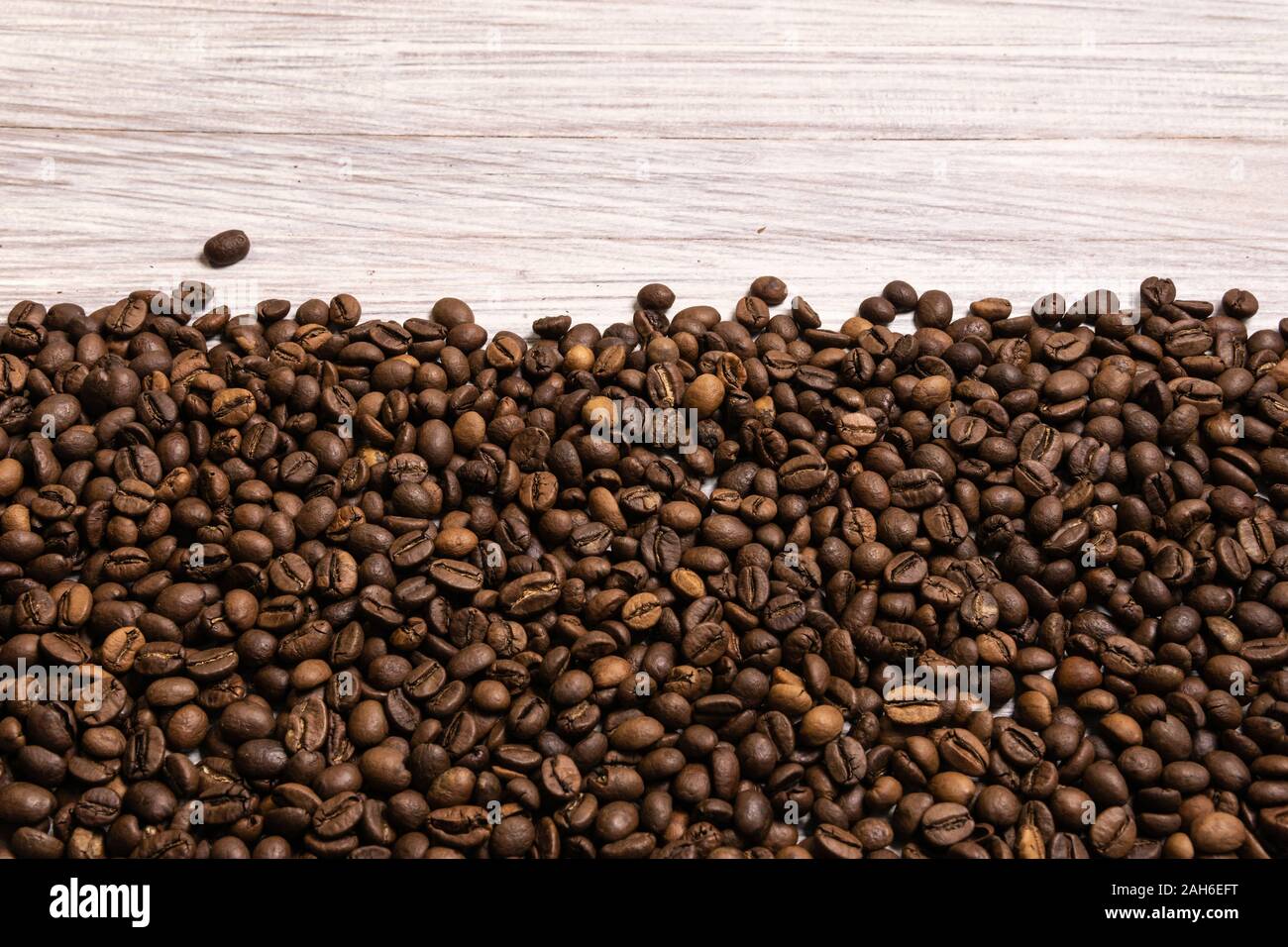 Roasted coffee beans in bulk on a light wooden background. dark cofee ...