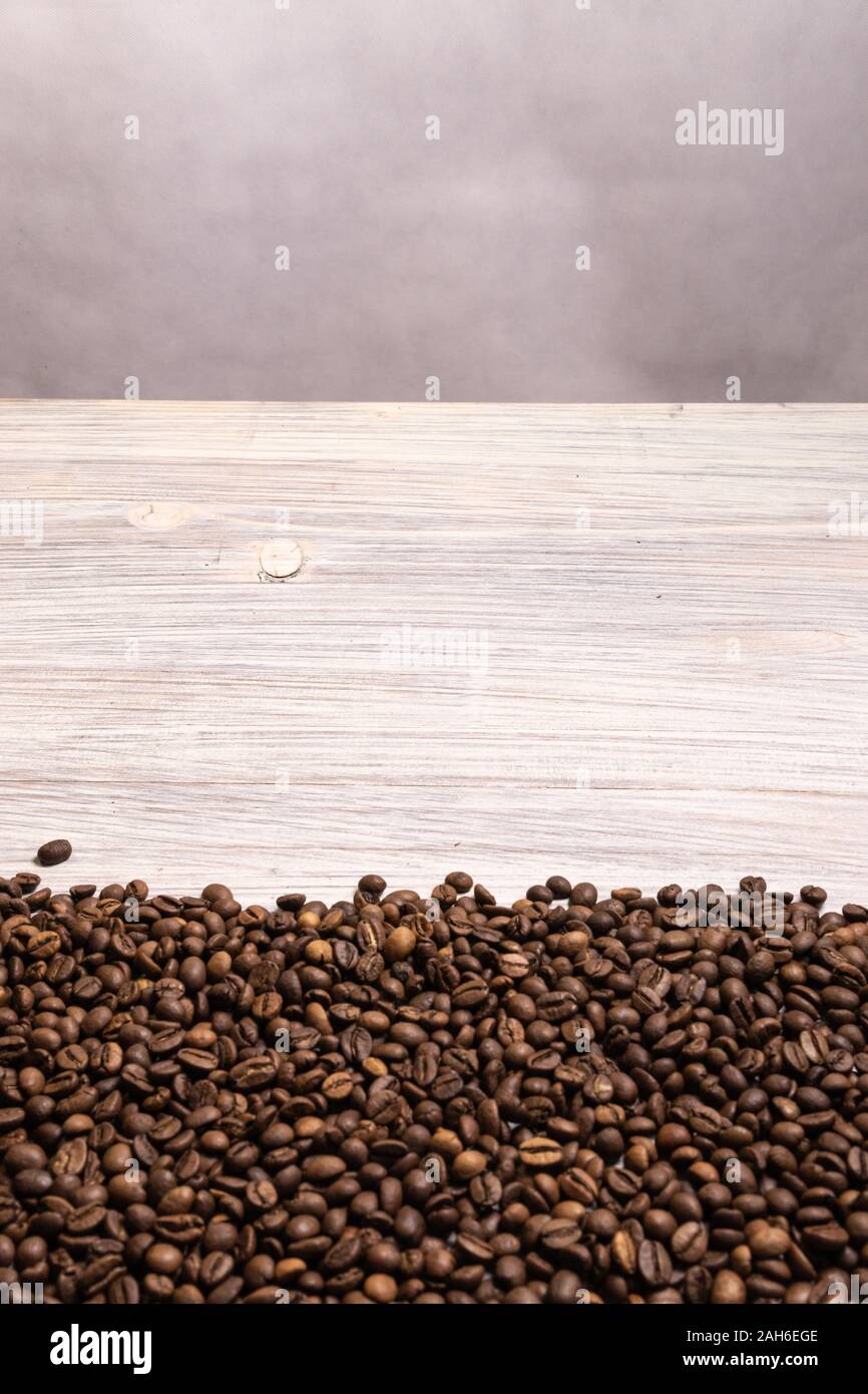 Roasted coffee beans in bulk on a light wooden background. dark cofee ...
