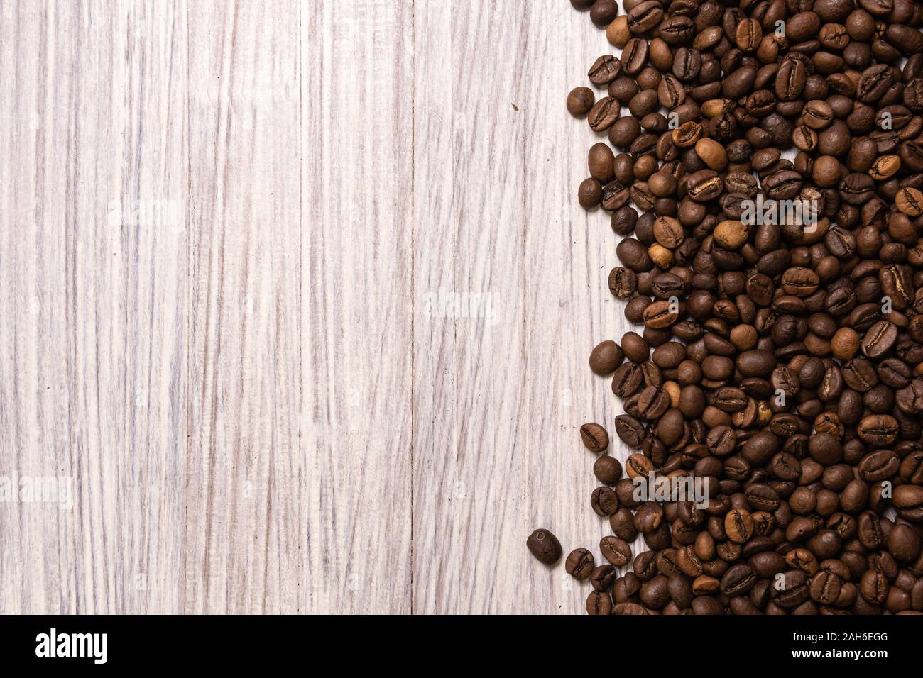Roasted coffee beans in bulk on a light wooden background. dark cofee ...