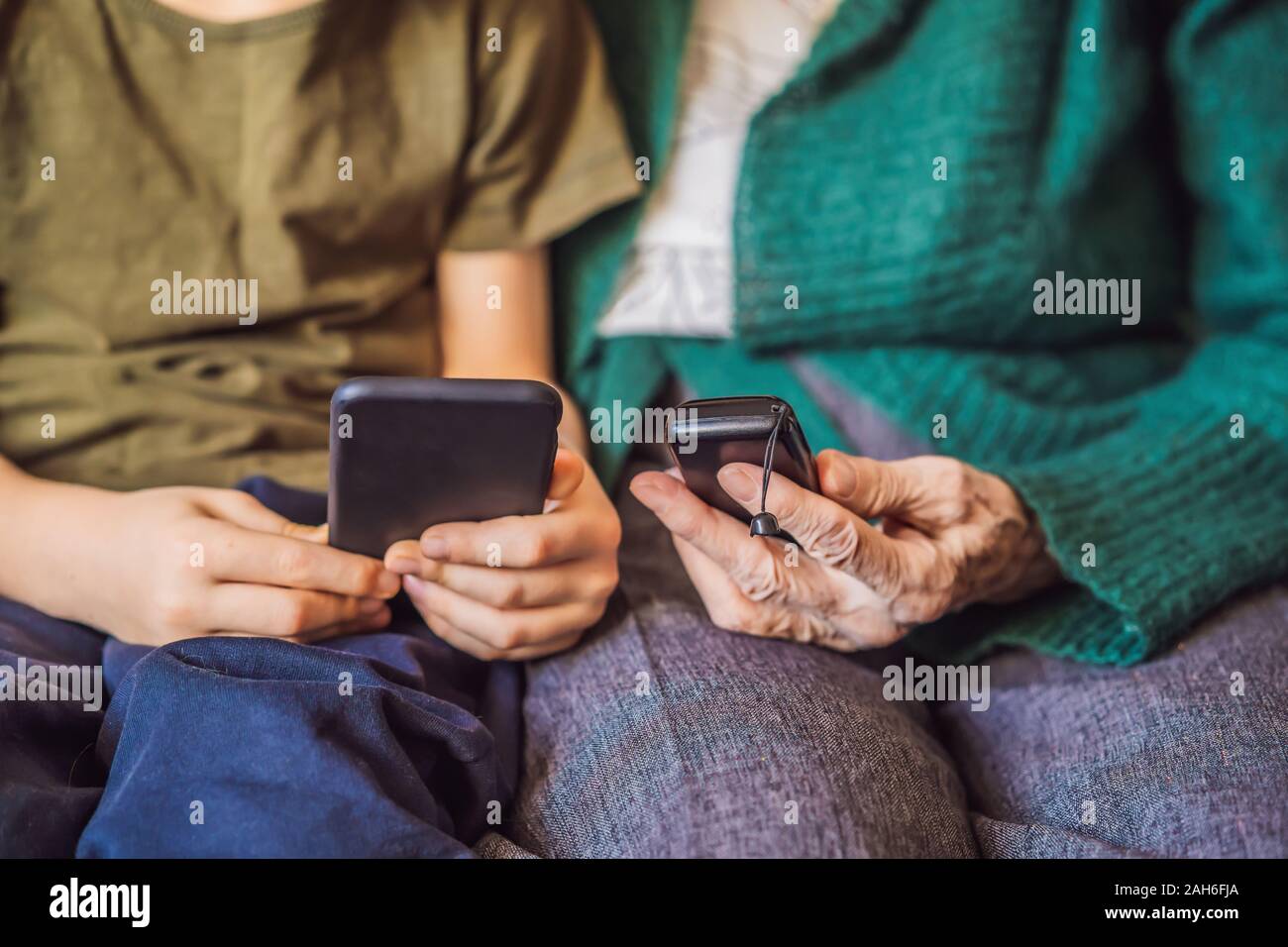Old woman uses an old phone, boy uses a smartphone Stock Photo