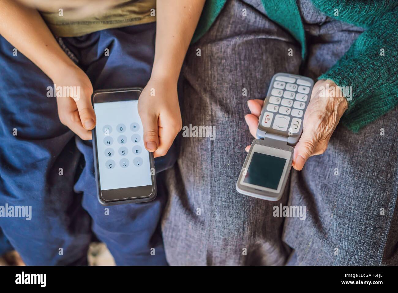 Old woman uses an old phone, boy uses a smartphone Stock Photo
