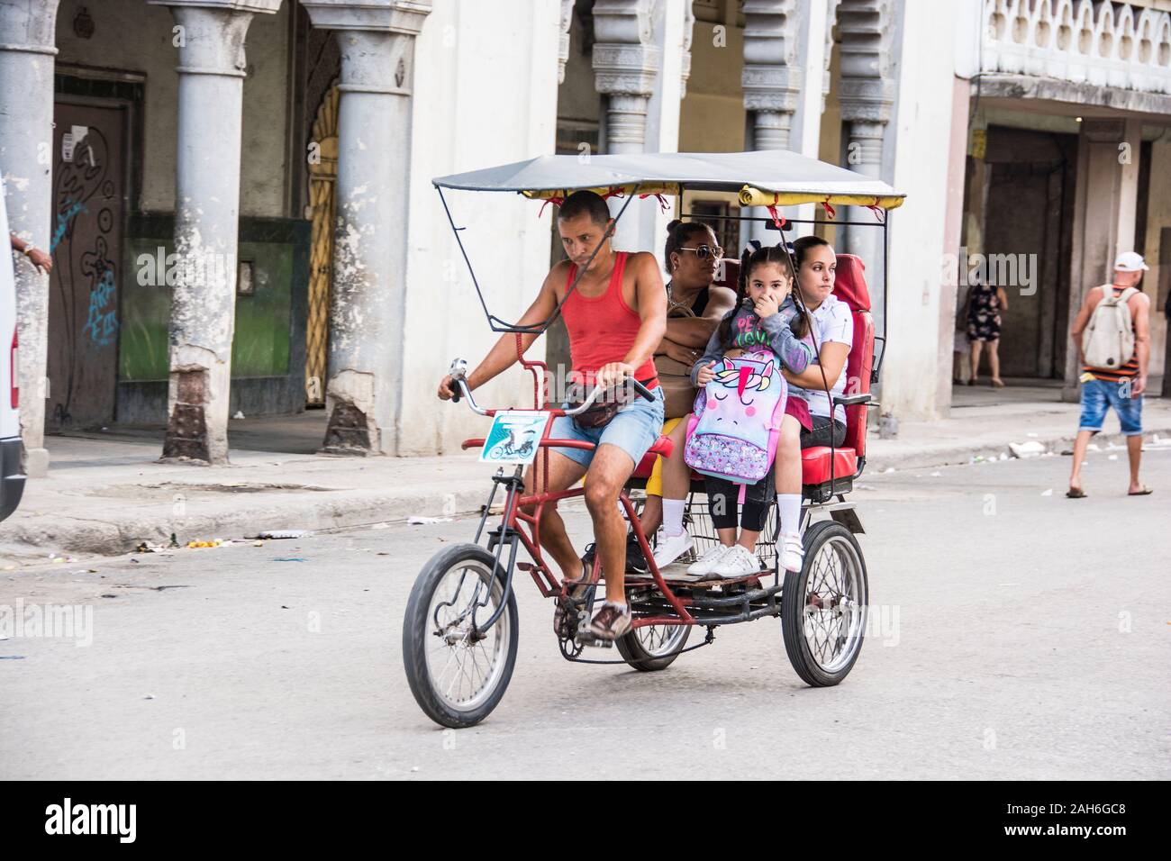 People of Havana Series - A Cuban taxi driver, with a load of passengers going down the street. Stock Photo