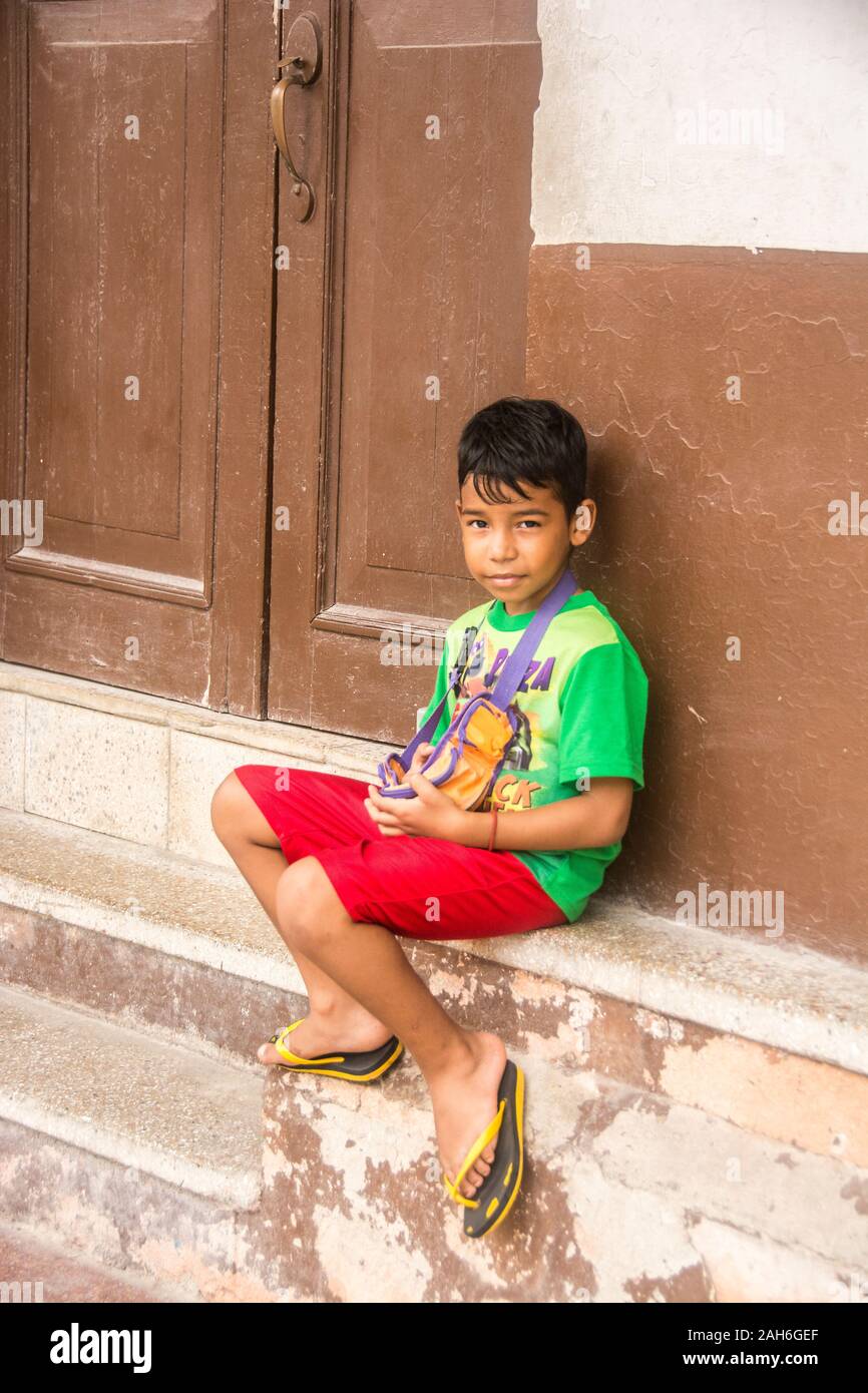 People of Havana Series - A young, boy sitting on the door stoop in front of his house. Stock Photo