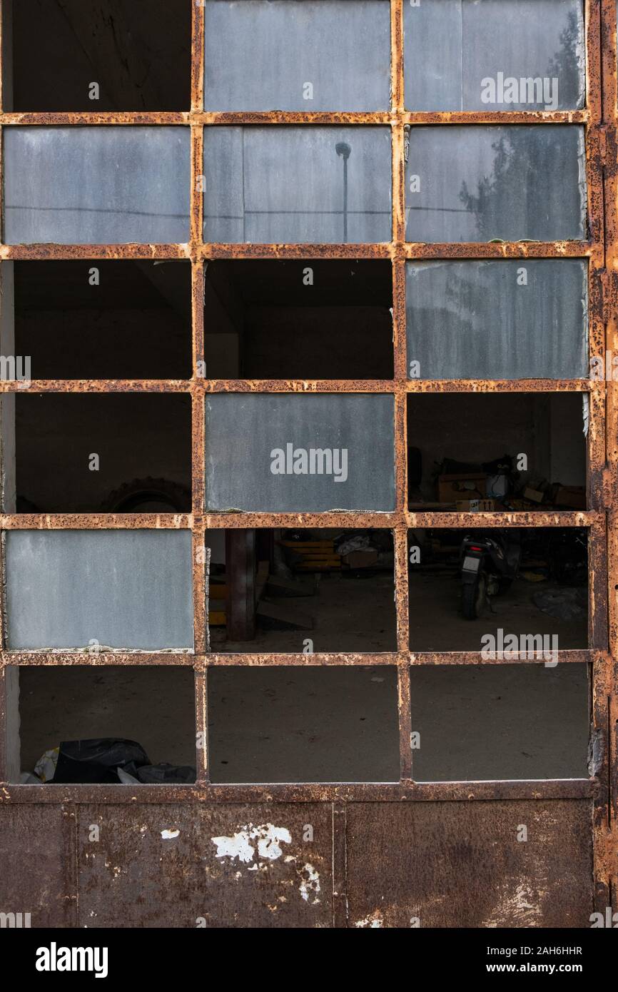 The broken windows and rusting frame of a door leading into a garage, nobody in the image Stock
