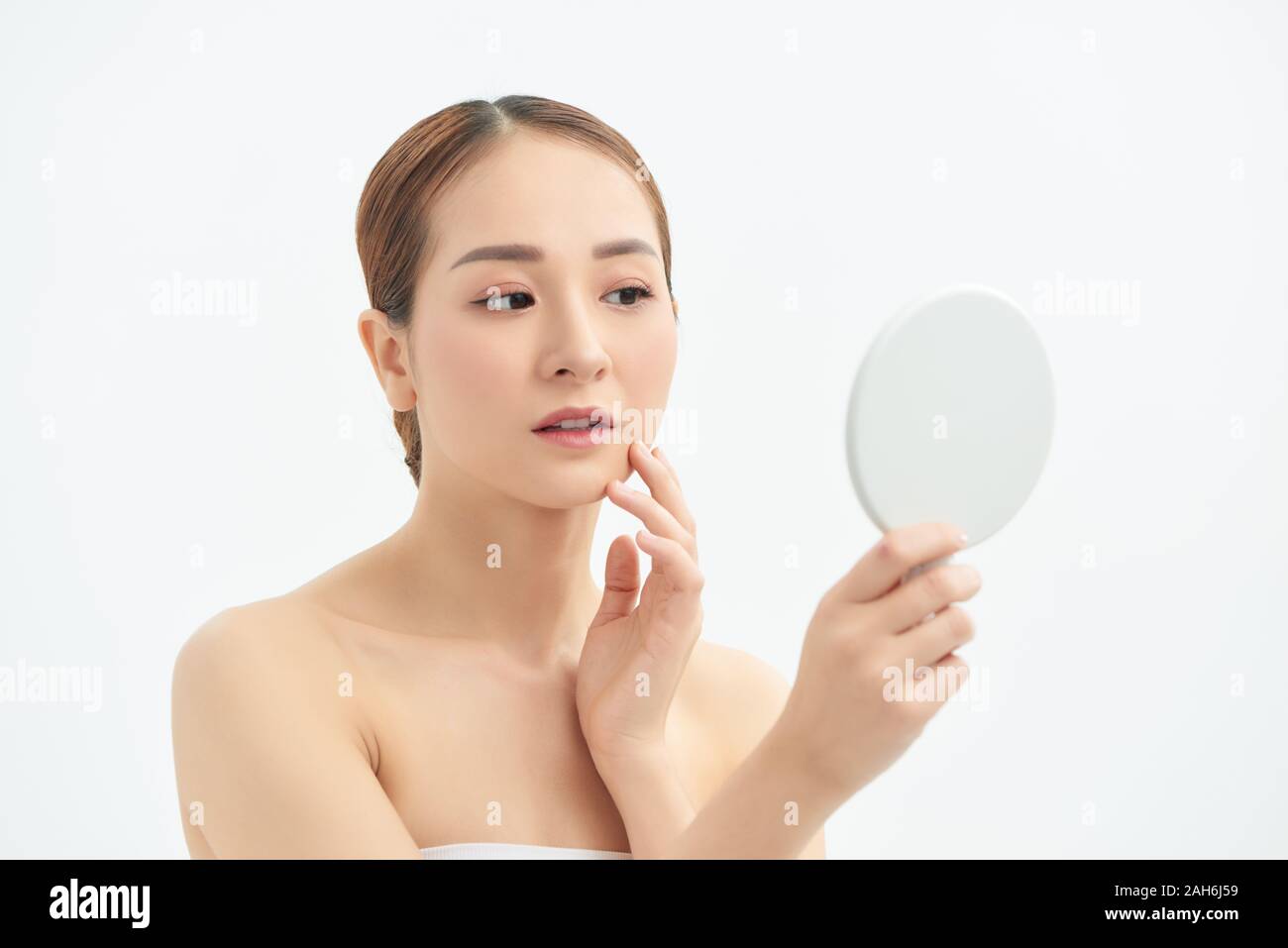 Beautiful Asian woman checking her skin, skin care, acne treatment. Spa and skincare concept. Stock Photo