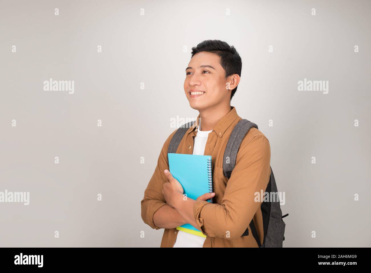 Portrait of smiling young college Asian student with books and backpack ...