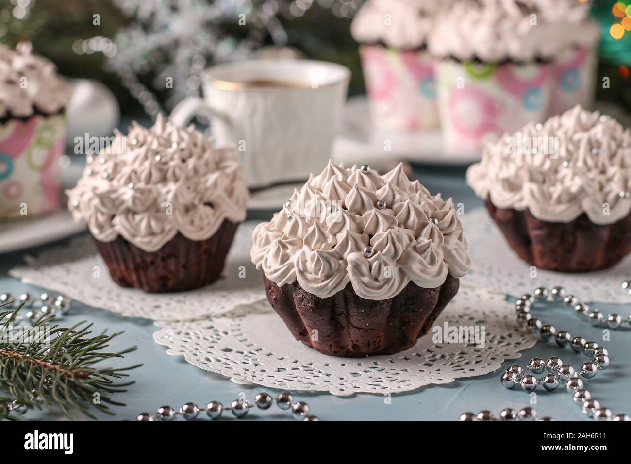 Homemade chocolate cupcakes with cream and a cup of coffee arranged on a light blue background, horizontal orientation Stock Photo