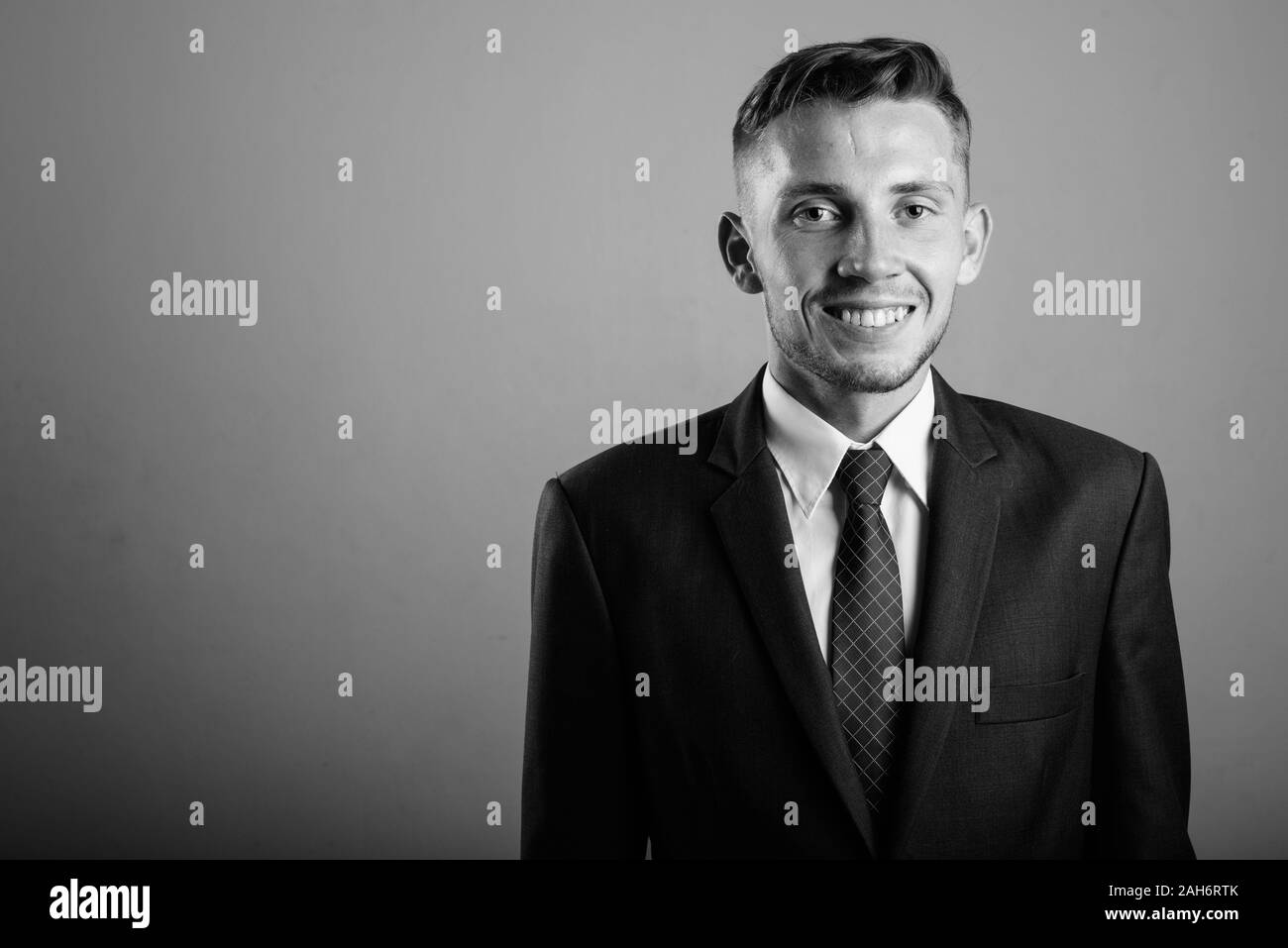Young businessman wearing suit against gray background Stock Photo - Alamy