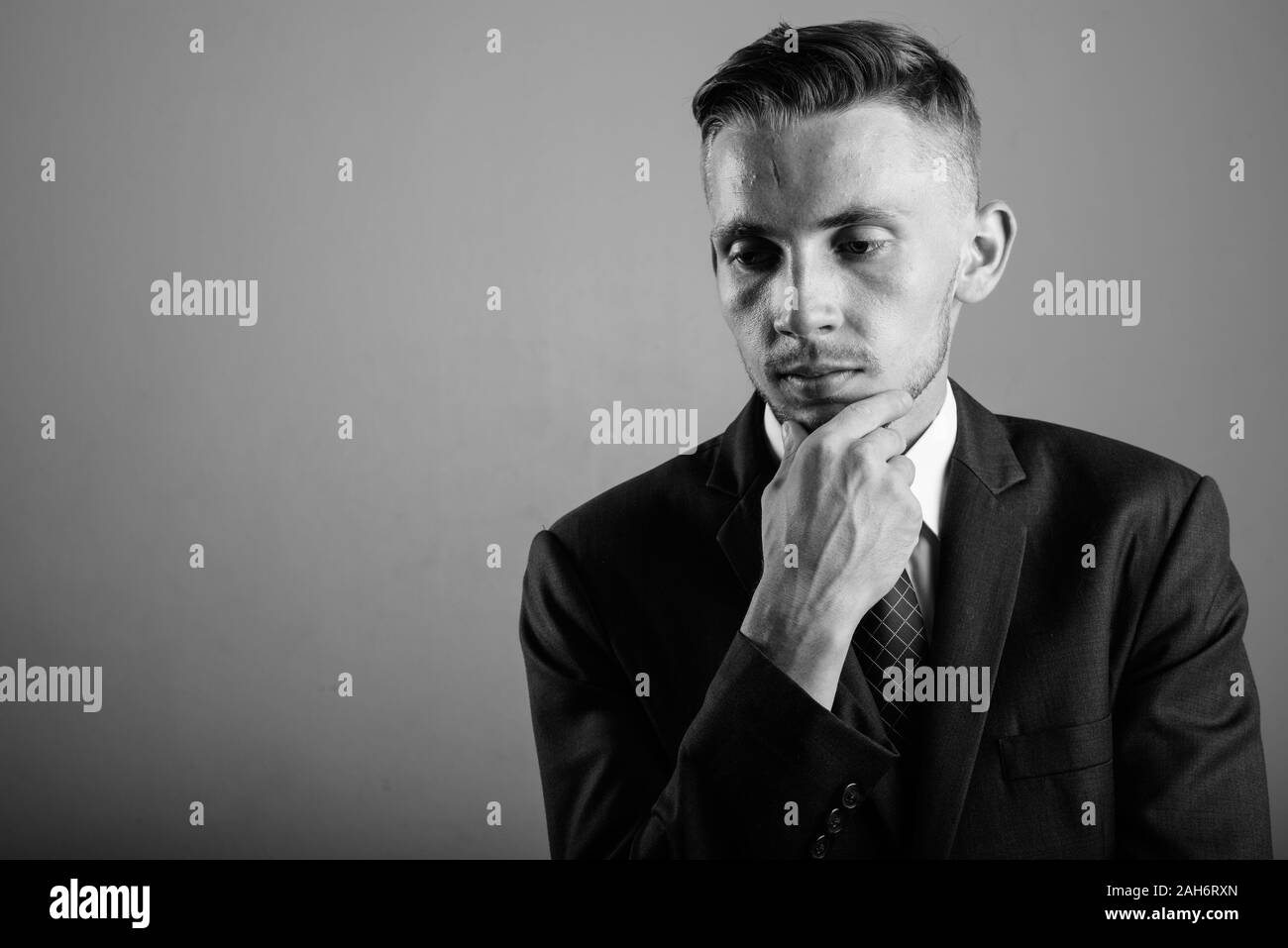 Young businessman wearing suit against gray background Stock Photo - Alamy