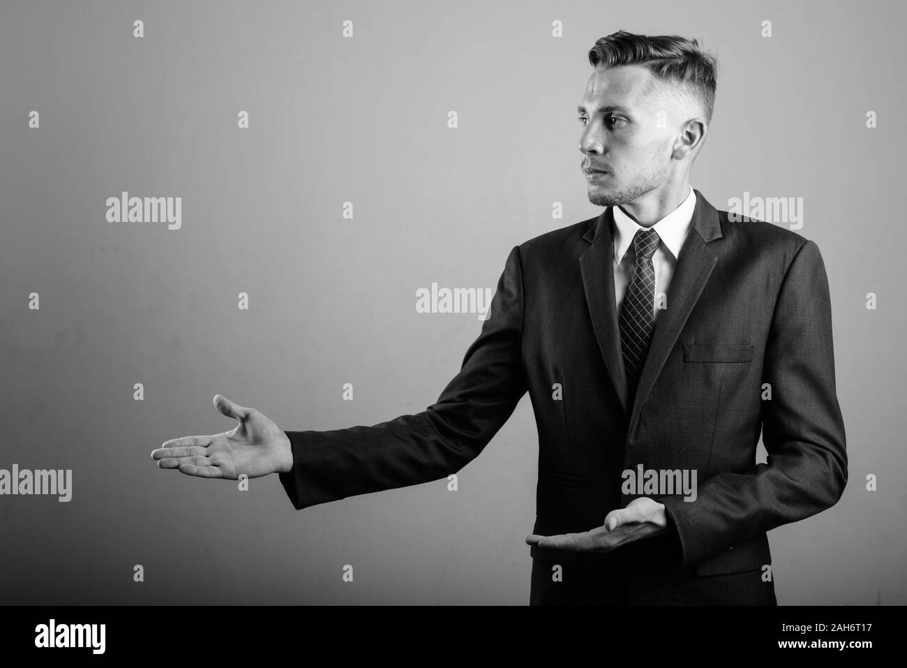 Young businessman wearing suit against gray background Stock Photo - Alamy