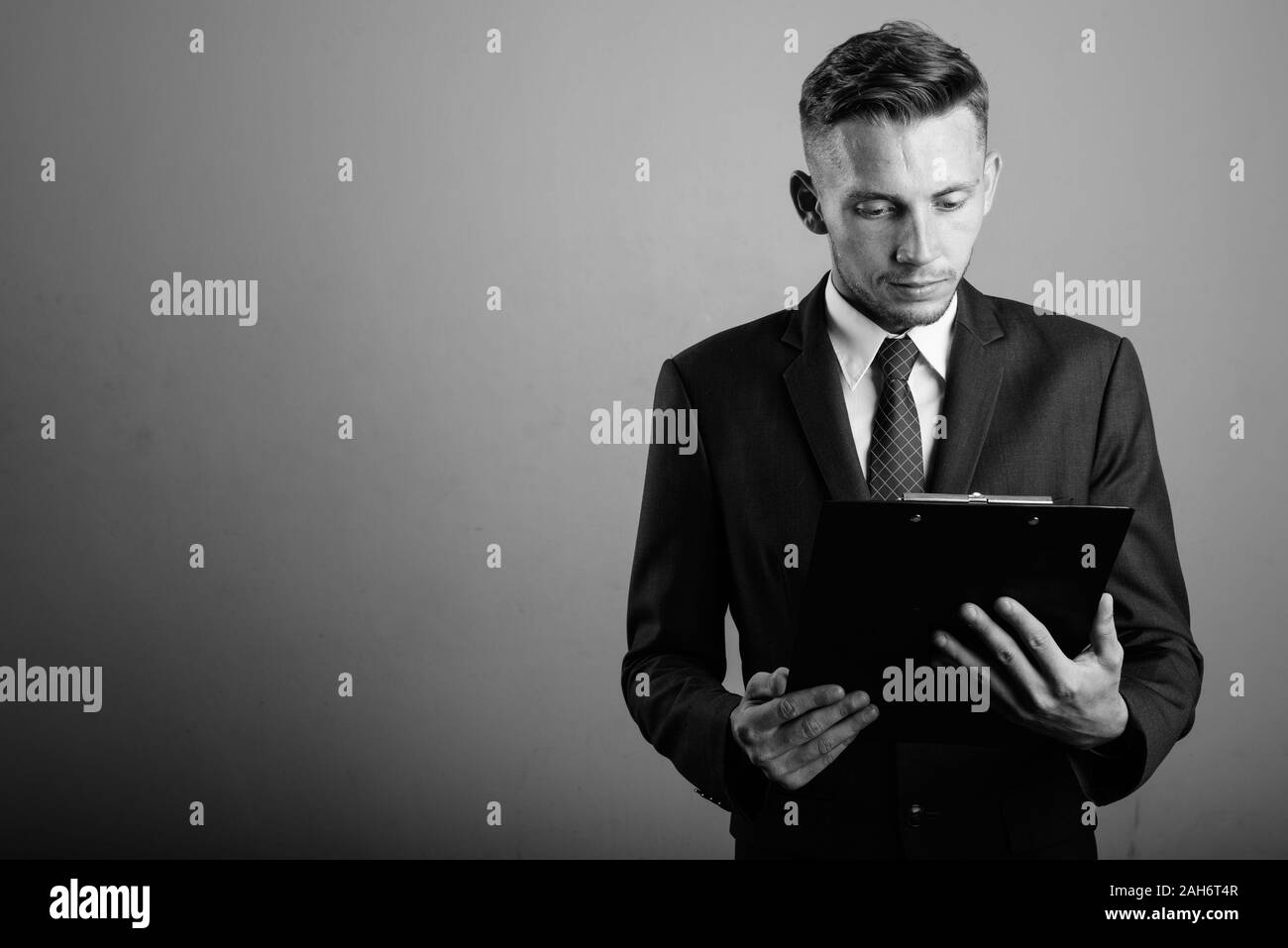 Young businessman wearing suit against gray background Stock Photo - Alamy