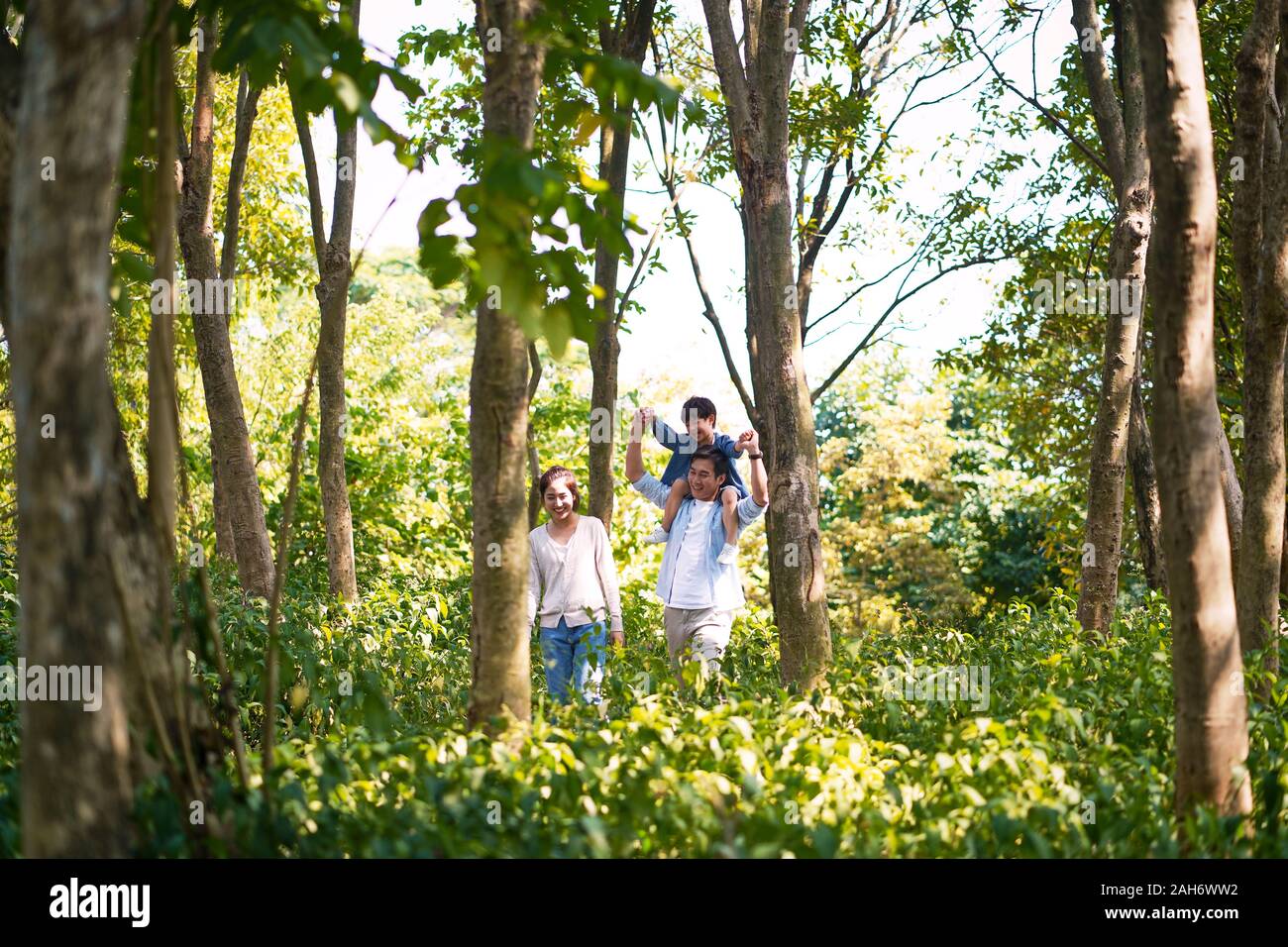 asian parents and child having fun walking outdoors in woods Stock Photo
