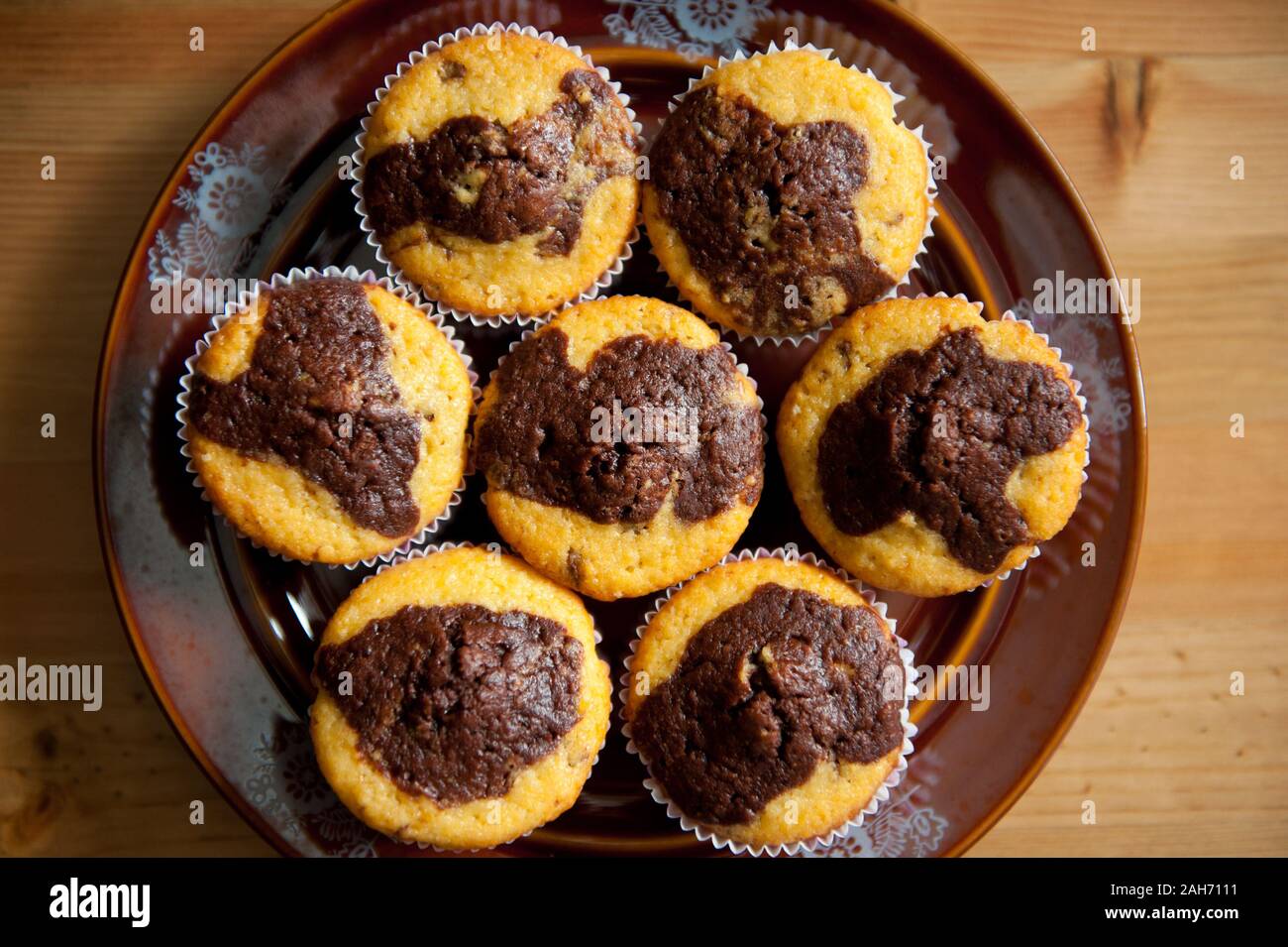 Lemon with chocolate taste muffins, few homemade delicious cupcakes lying on dark brown plate on table, sweet treats view from above, baked food. Stock Photo